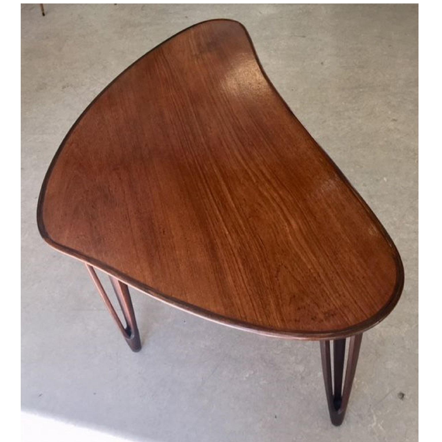 Danish Mid-Century Modern biomorphic coffee / lounge table in teak produced by BC Møbler in the 1950s. The soft, biomorphic triangular shape top features a contrasting raised lip. The table is supported by three trident shaped legs capped in brass.