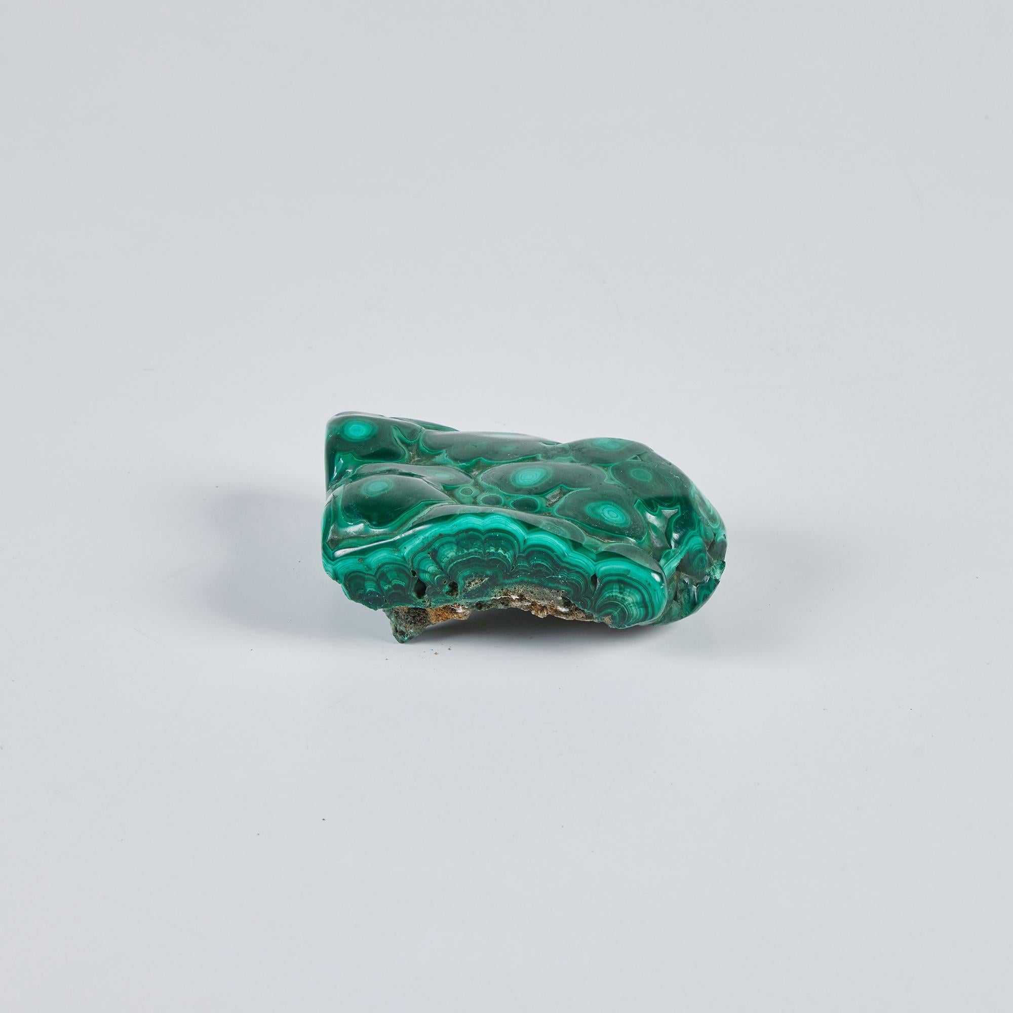 Biomorphic Malachite sculpture has a polished surface and raw rock bottom. The opaque polished stone features round patterned top and a textured underside. A playful sculpture or paper weight.

Dimensions
4.5