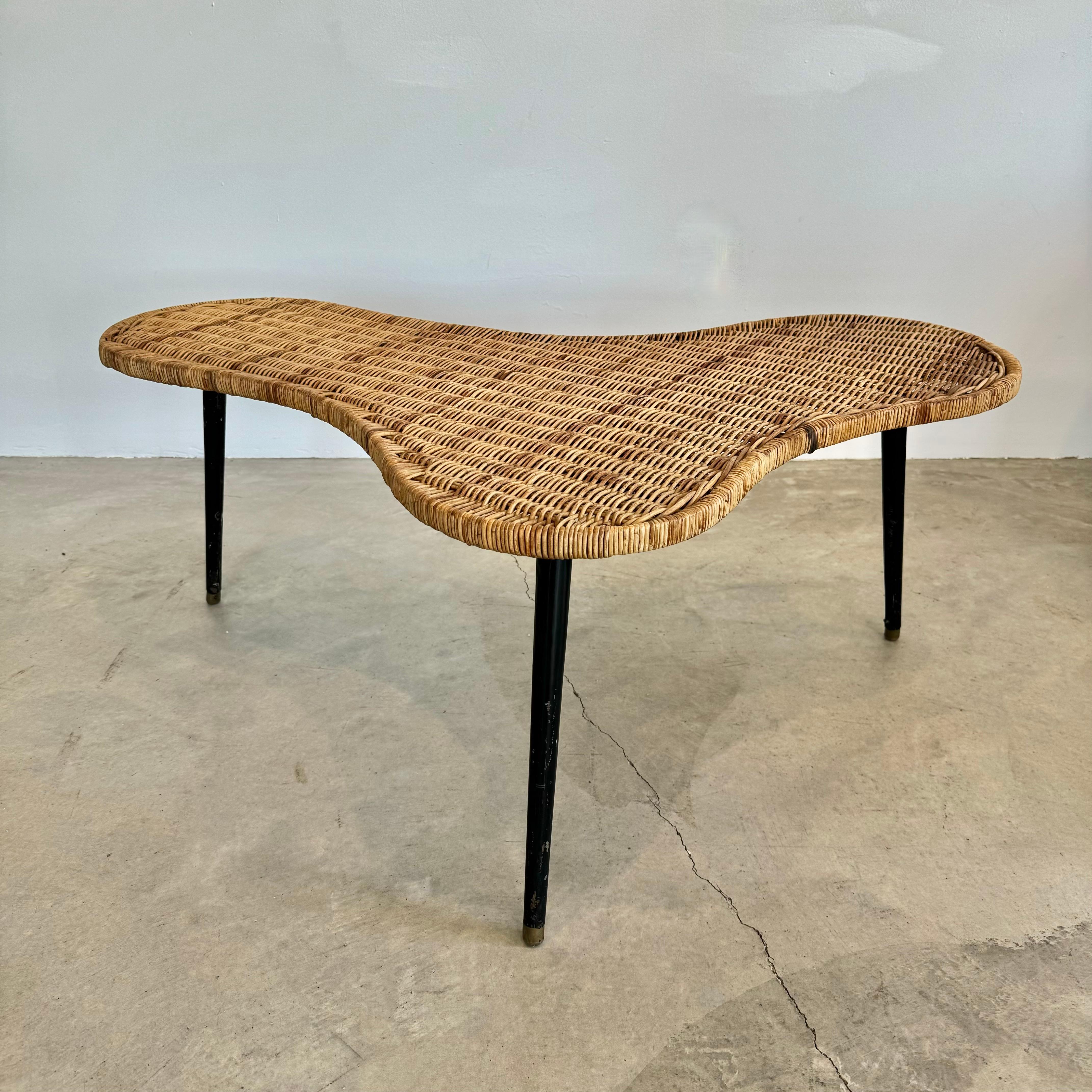 Sculptural wicker and iron coffee table made in France, circa 1950s. Biomorphic amoeba shape. Supported underneath with iron bars extending throughout. Table sits atop three thick iron legs. In the style of T.H Robsjohn-Gibbings and Raoul Guys. Both