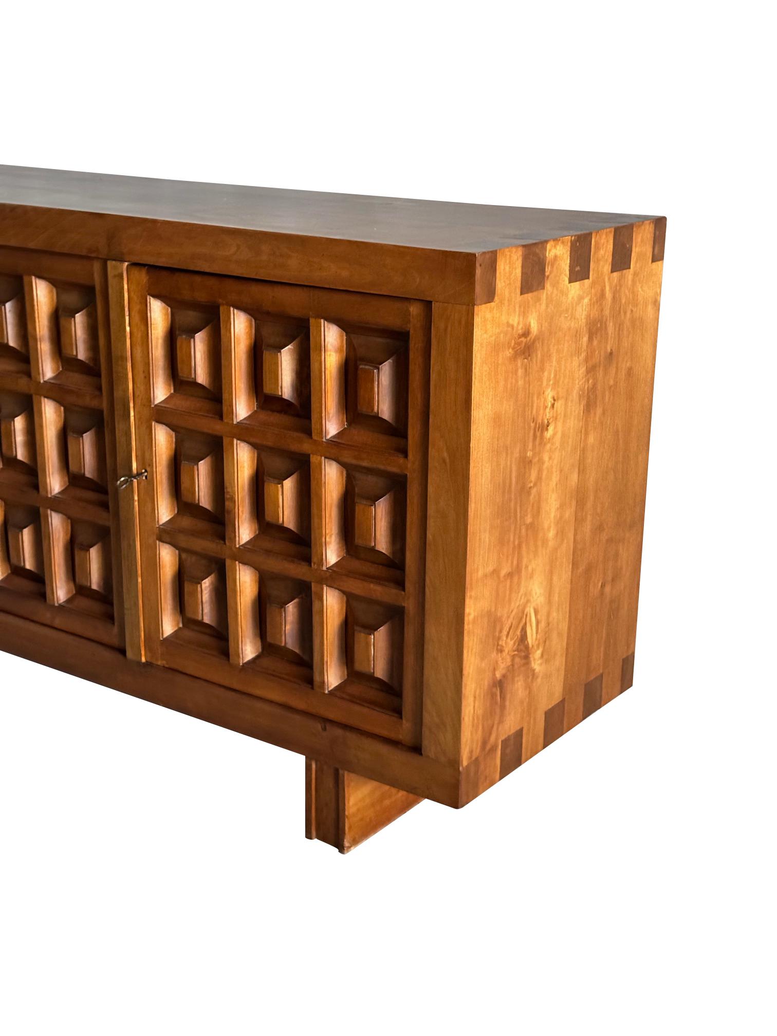 1950's Spanish Biosca three door credenza.
The doors feature a relief surface of graphic 3D squares.
Typical Brutalist style.
Decorative dovetail joints.
Stained pine.
One interior shelf and five drawers.
