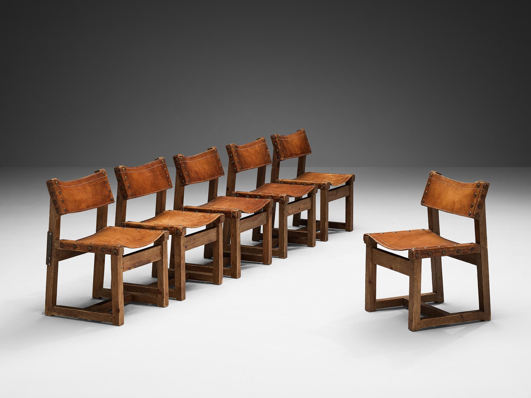 Biosca, Satz von sechs Stühlen, Leder, Eiche, Messing, Spanien, 1960er Jahre 

Robuste Stühle, hergestellt von der spanischen Firma BIOSCA. Diese Stühle sind aus Eichenholz gefertigt und mit cognacfarbenen Ledersitzen ausgestattet. Die Stühle haben