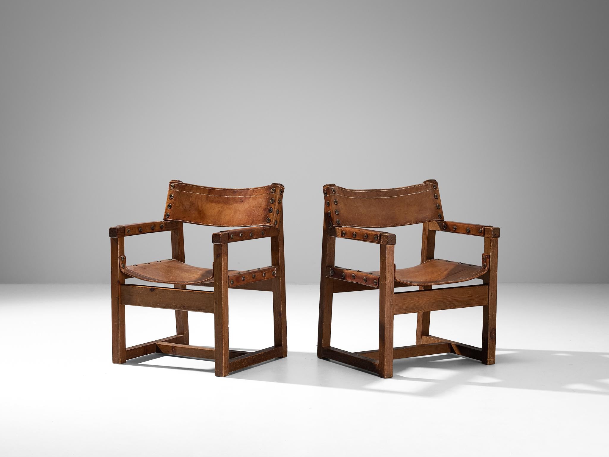 Biosca, pair of armchairs, saddle leather, pine, brass, Spain, 1950s 

Sturdy chairs manufactured by the Spanish Biosca. These chairs are made out of pine and have stunning, cognac leather seating in patinated condition. The chairs have a robust