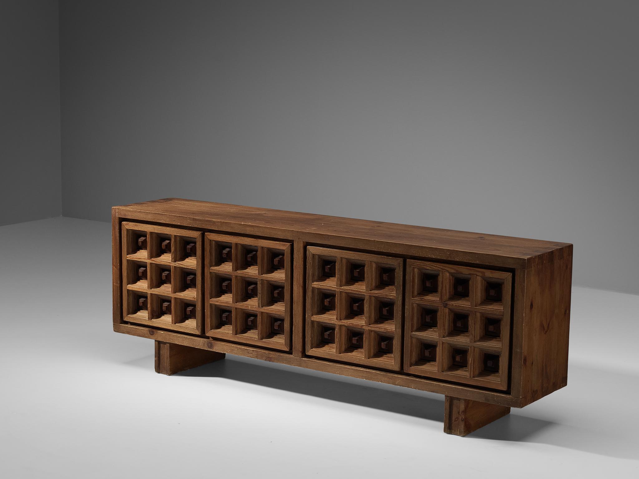 Biosca, sideboard, stained pine, Spain, 1960s.

Outstanding Spanish sideboard that is executed by Biosca in a beautiful way. The door panels feature a relief surface of graphic carved squares. This is very typical for Brutalist style, while the
