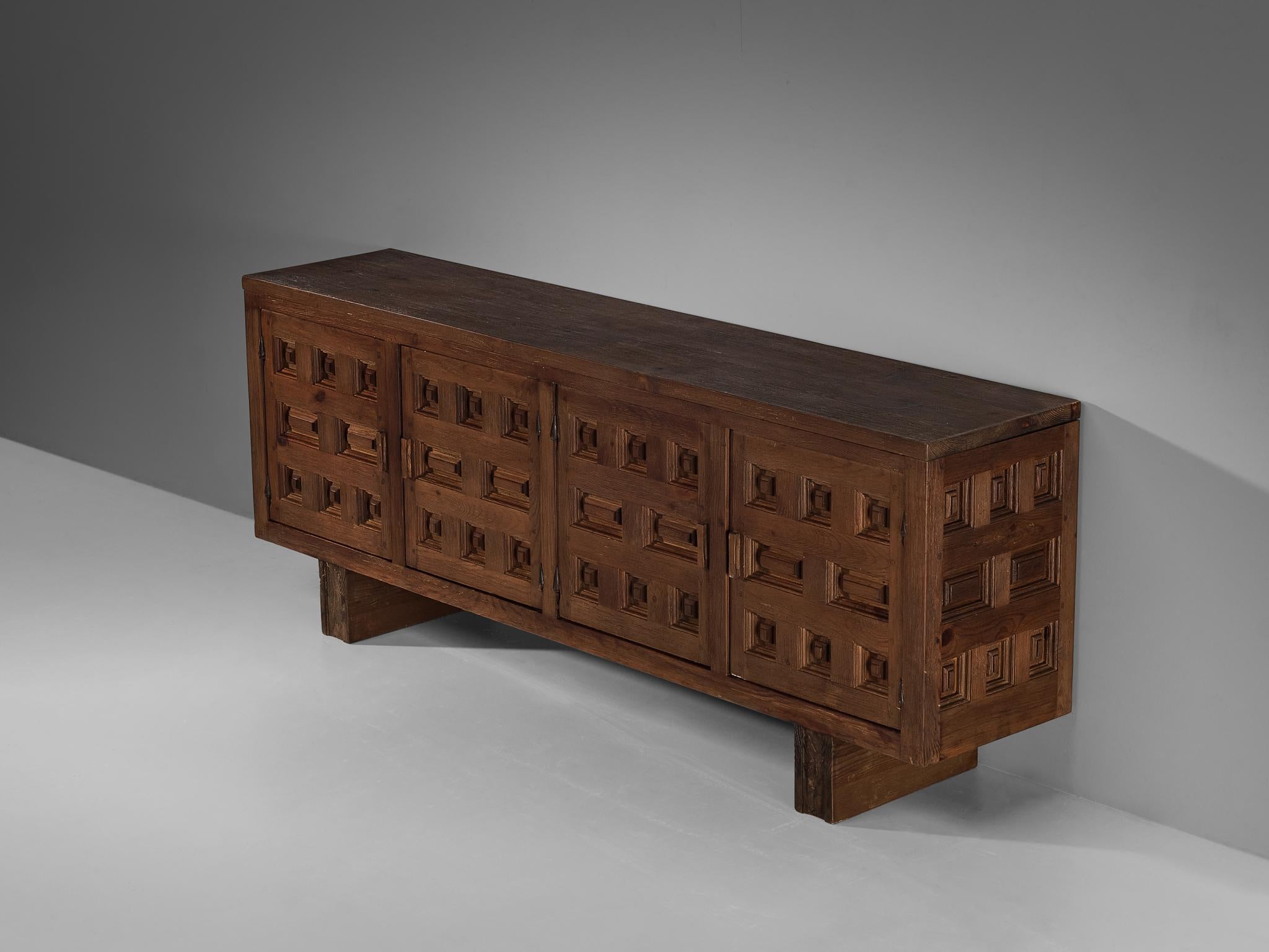 Biosca, sideboard, stained pine, Spain, 1960s.

Outstanding Spanish sideboard that is executed by Biosca in a beautiful way. The door panels feature a relief surface of graphic carved figures, alternating between rectangular and square shapes. This