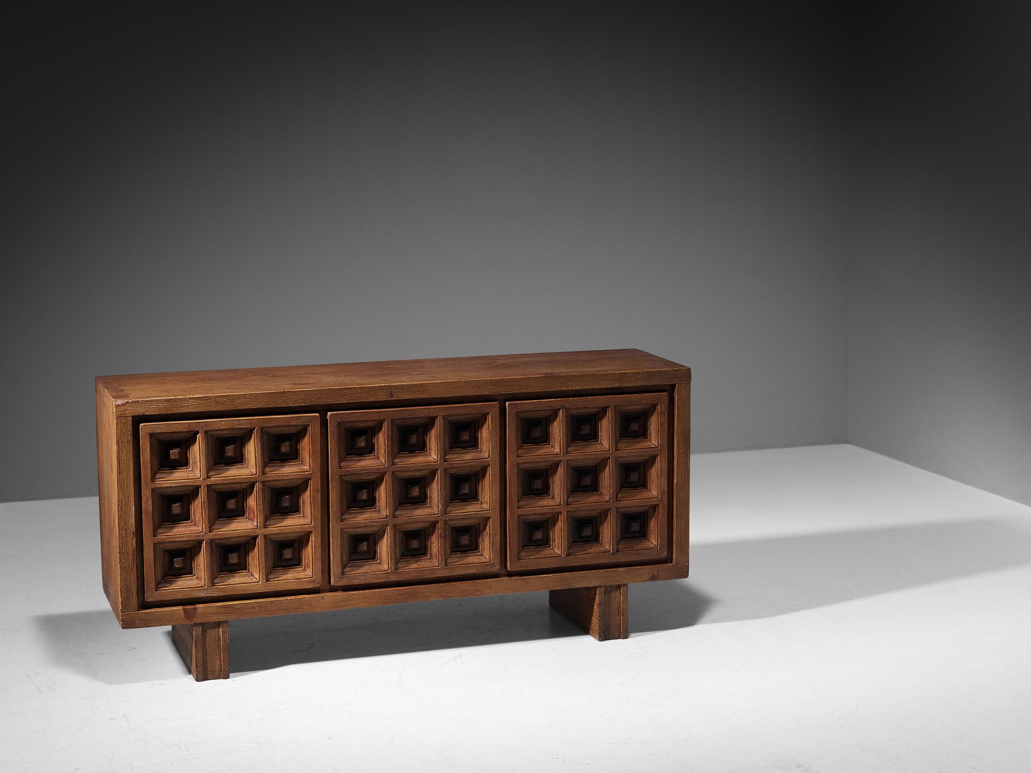 Biosca, sideboard, stained pine, Spain, 1960s.

Outstanding Spanish sideboard that is executed by Biosca in a beautiful way. The door panels feature a relief surface of graphic carved squares. This is very typical for Brutalist style, while the type