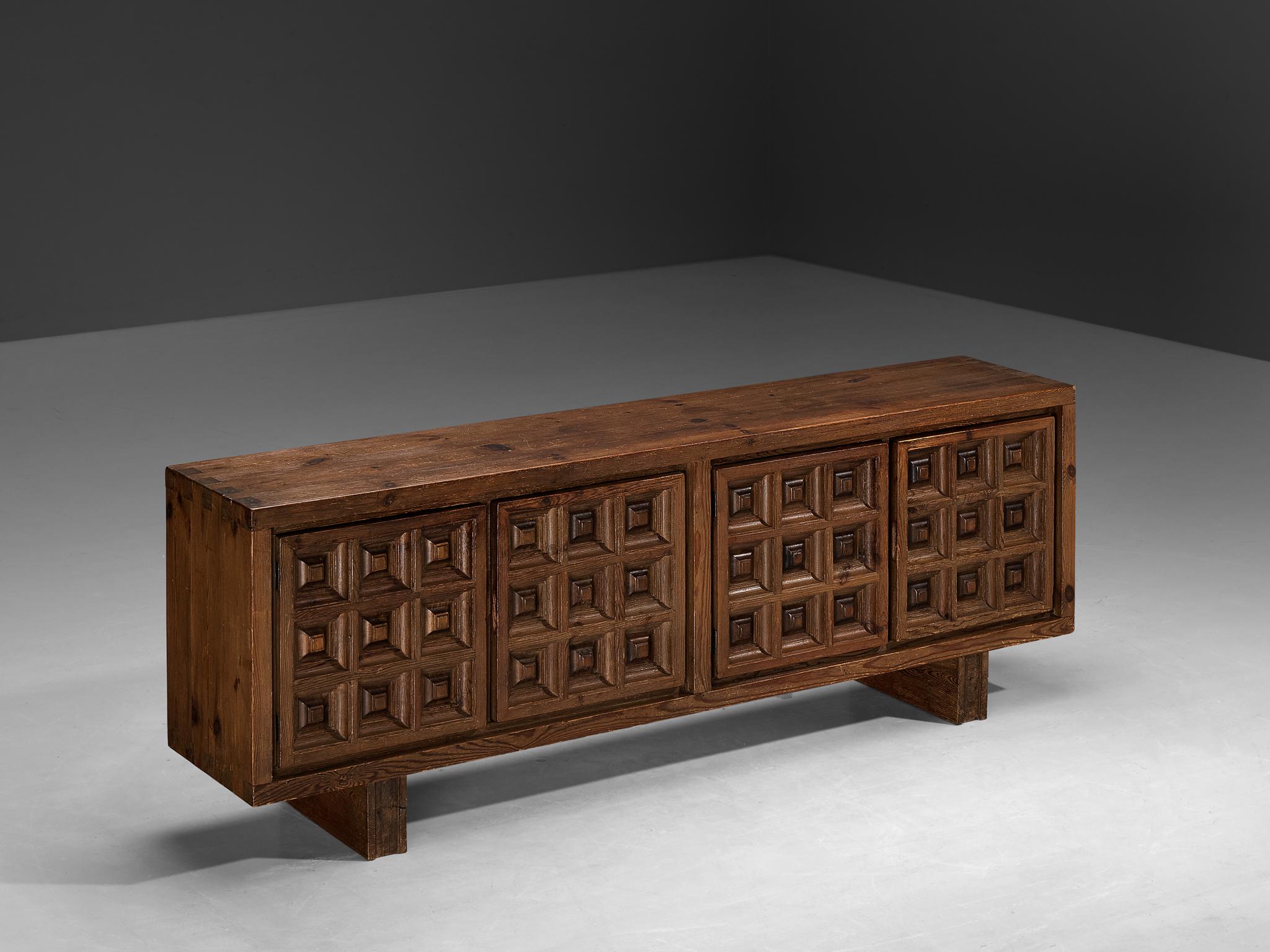 Biosca, sideboard, stained pine, Spain, 1960s.

Outstanding Spanish sideboard that is executed by Biosca in a beautiful way. The door panels feature a relief surface of graphic carved squares. This is very typical for Brutalist style, while the type