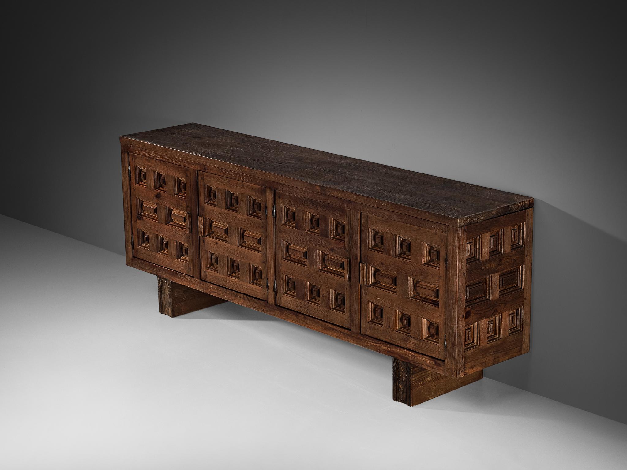 Biosca, sideboard, stained pine, Spain, 1960s.

Outstanding Spanish sideboard that is executed by Biosca in a beautiful way. The door panels feature a relief surface of graphic carved figures, alternating between rectangular and square shapes. This