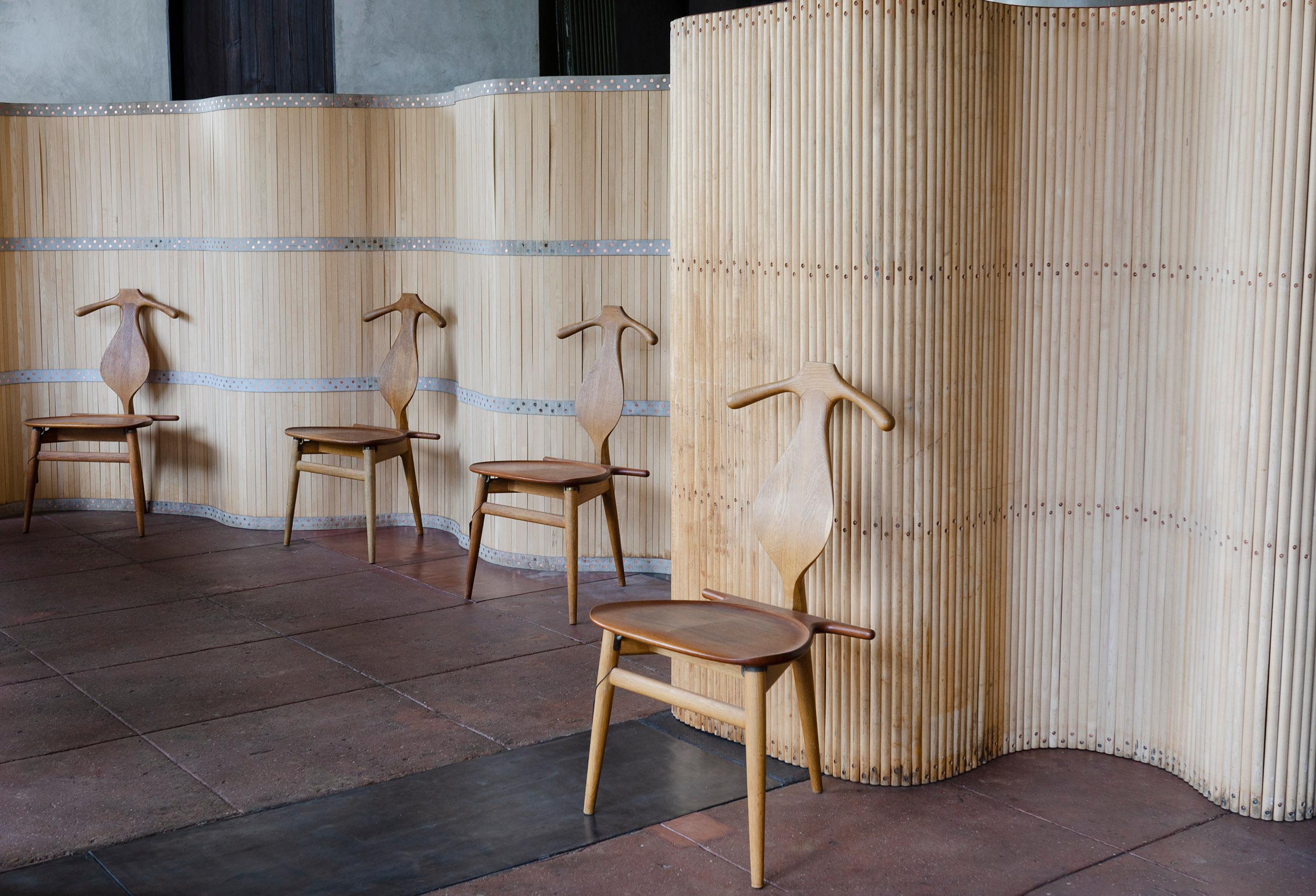 A room divider or screen fashioned from a birch conveyor belt, the birch slats joined by riveted bands of leather.