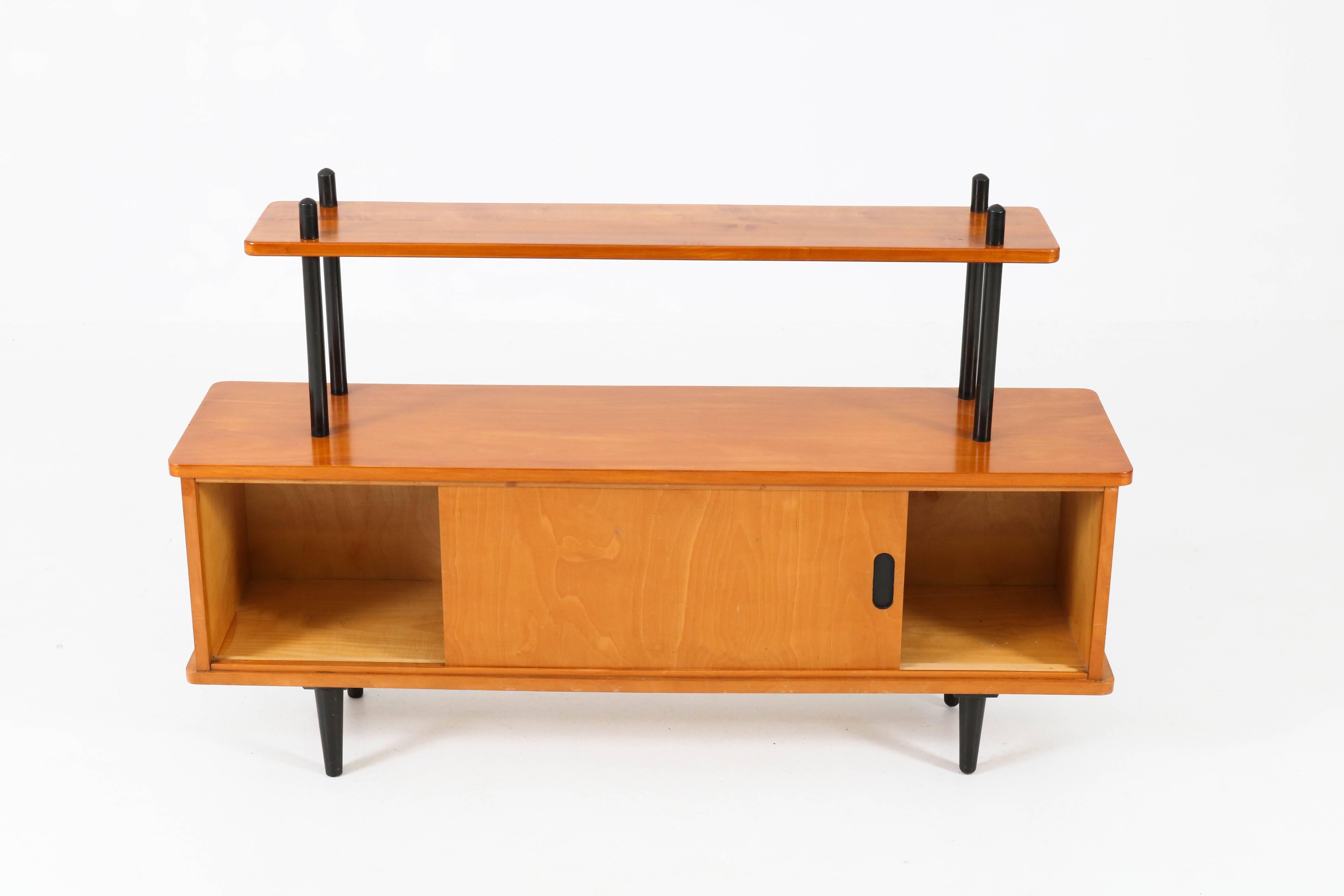 Stunning and rare Mid-Century Modern bookcase or credenza in the style of Lutjens, 1950s.
Birch with original ebonized beech stands.
Two original sliding doors.
In good original condition with minor wear consistent with age and use,
preserving a