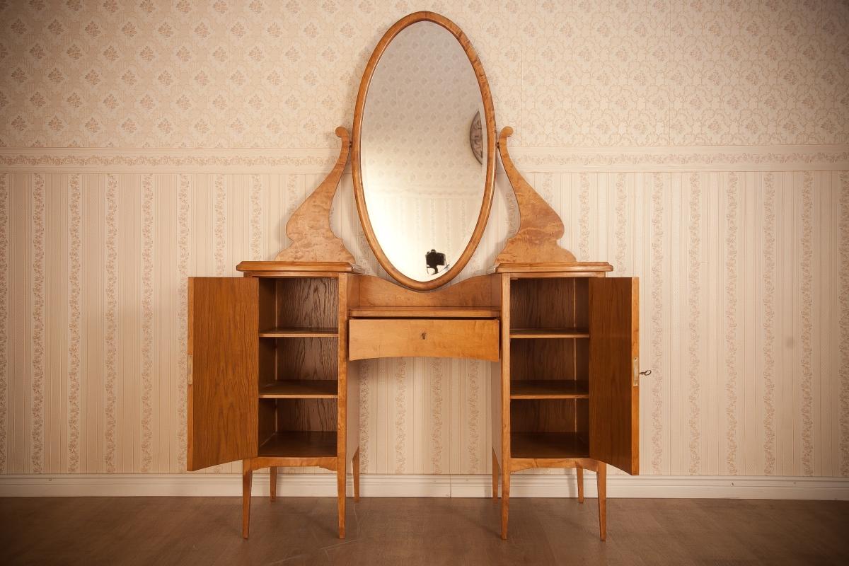 We present you a lady’s vanity table, circa 1920, in birchen veneer.
Because of the shape of the mirror, it is called Psyche.
The base is made of two cabinets on high legs that are connected with a drawer, which is lower in comparison to the