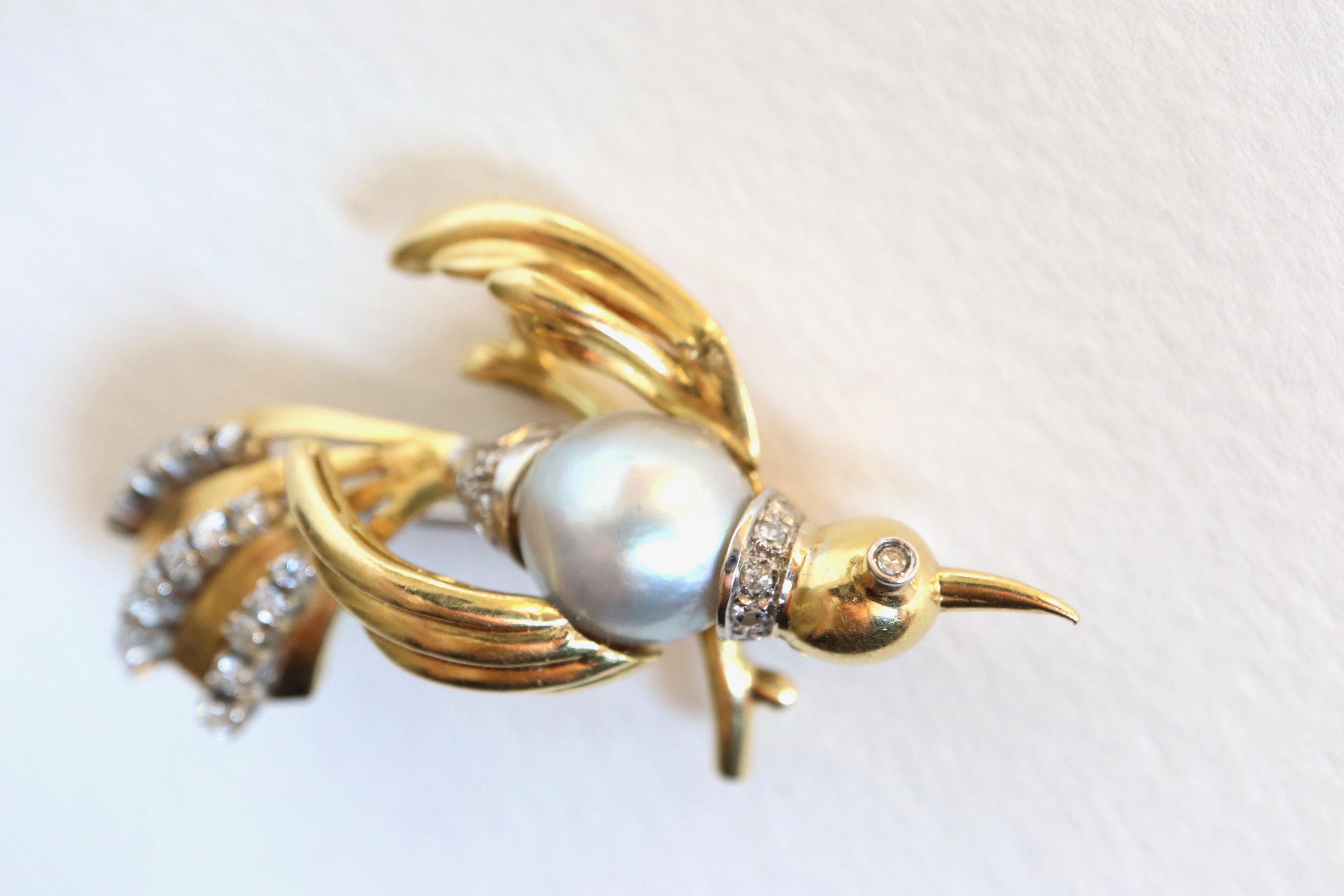 Antique Bird brooch circa 1960 in 18 Kt yellow gold and 18 carats white gold, set in its center with a gray pearl forming the body of the bird surrounded by diamonds. The tail of the bird is formed of stylized feathers in yellow gold interspersed