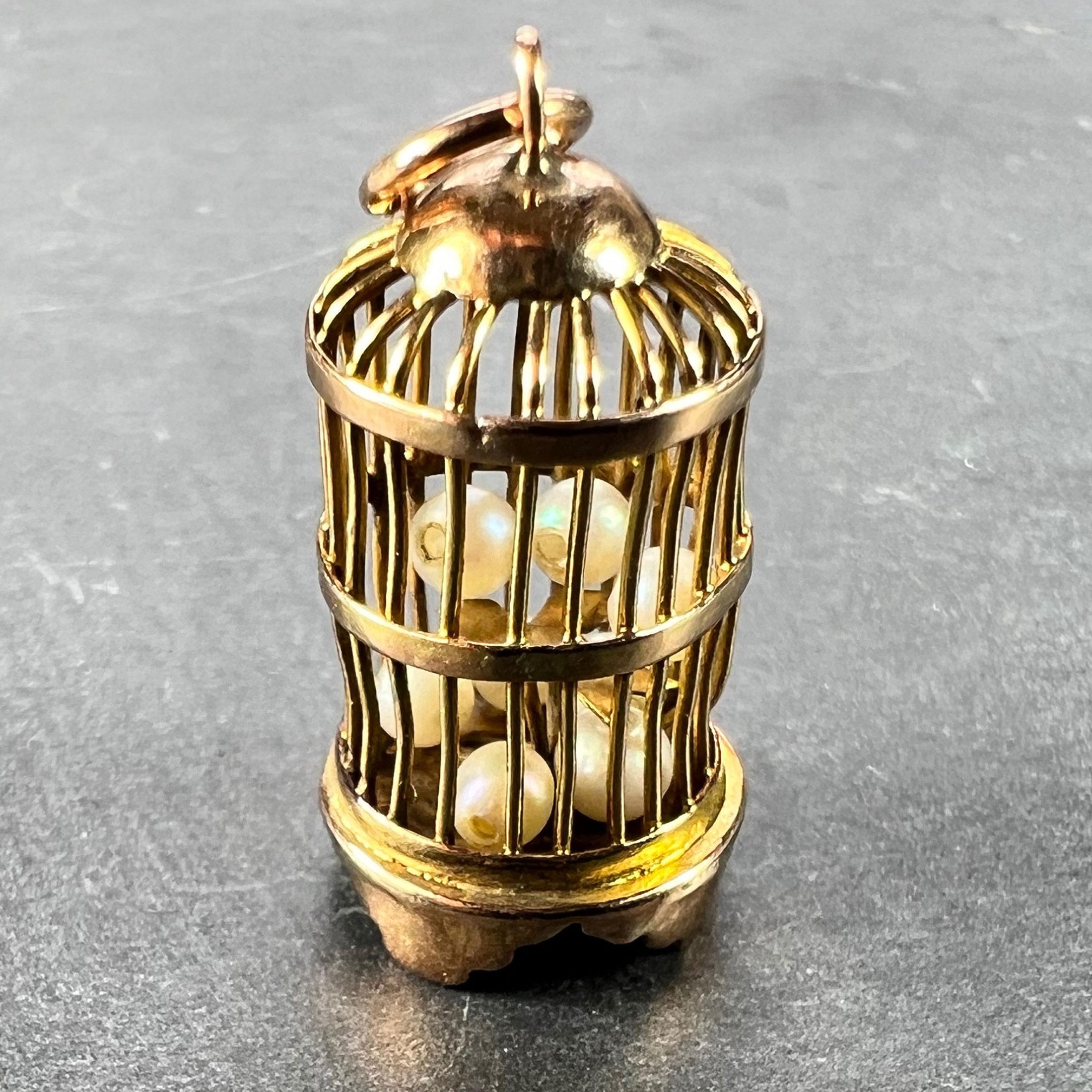 A 14 karat (14K) yellow gold charm pendant designed as a bird cage containing eight loose drilled cultured pearls. Stamped 14K for 14 karat gold to the base. 

Dimensions: 2 x 1 x 1 cm (Not including jump ring)
Weight: 1.63 grams
(Chain not