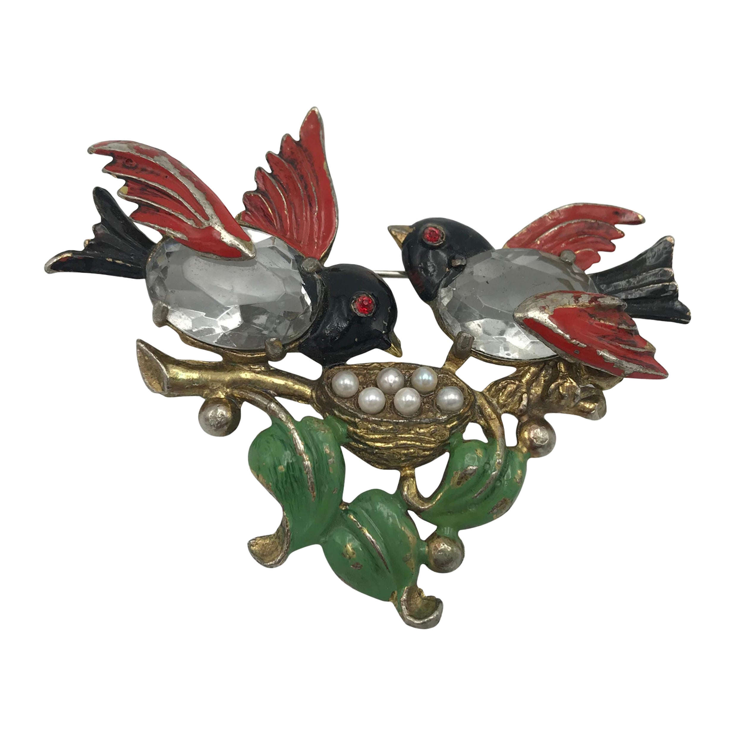 ¡Un adorable broche con 2 pájaros que cuidan juntos de su tesoro!
Los padres de los pájaros se sientan en una rama y cuidan de sus huevos. Los cuerpos de los 2 pájaros son de 2 brillantes, las alas, la cabeza y las colas y las hojas están