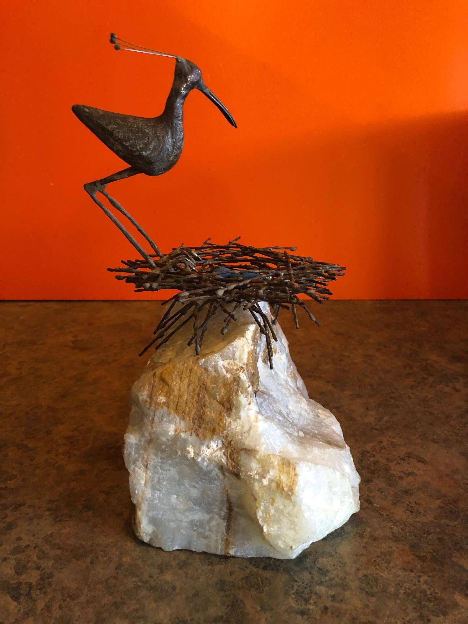 A very cool bird or sandpiper in nest sculpture on a solid block of white quartz by Curtis Jere, circa 1969. The bird and nest are made of welded metal with a gold overlay and there are three light blue eggs in the nest. The piece is signed 