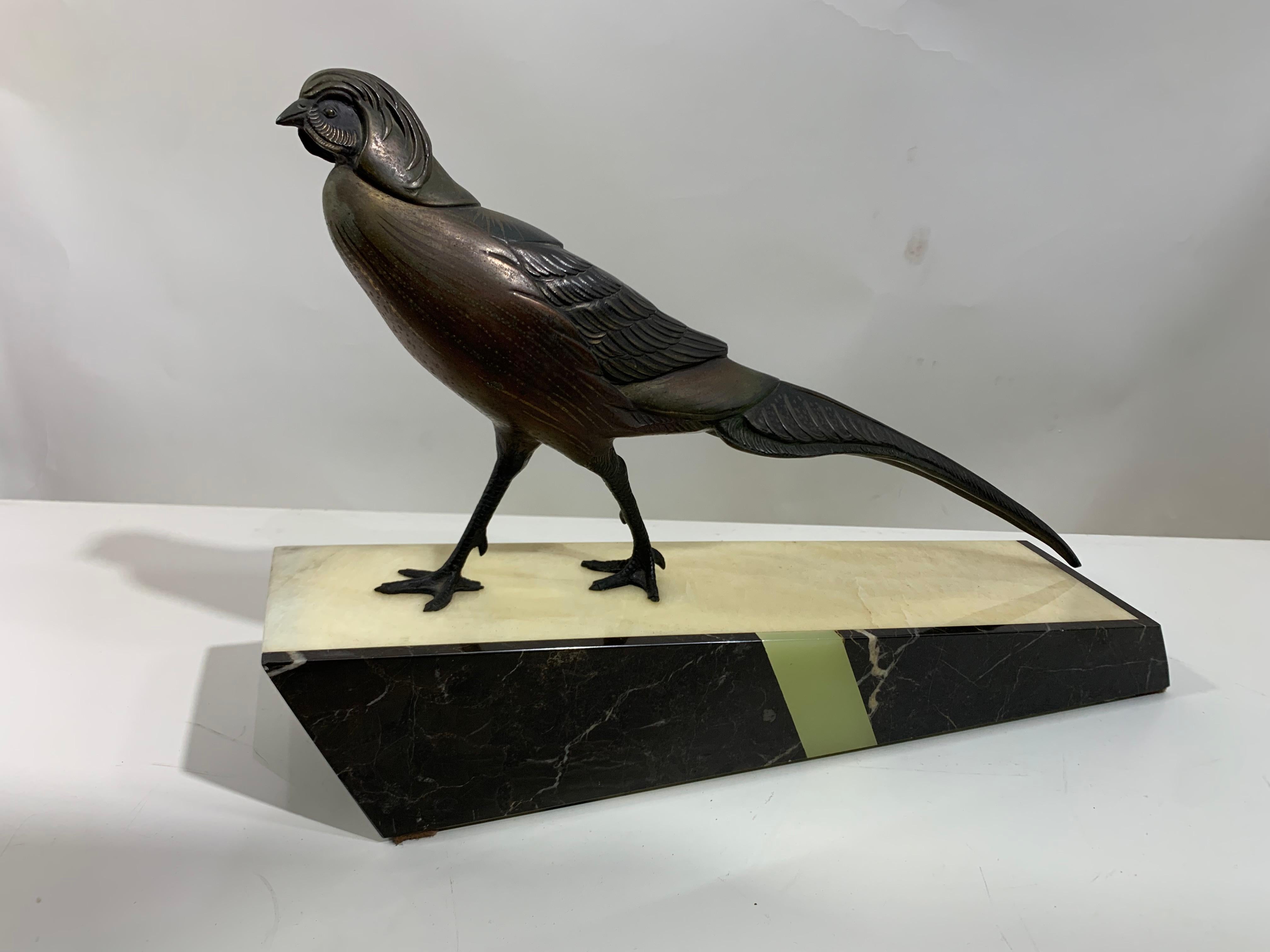 French sculpture of a bird standing proud on a polychromed marble pedestal. The statue is in a two-toned patinated bronze, representing a pheasant walking with its wings tucked in and its tail holding balance. 
Irénée Rochard was a French