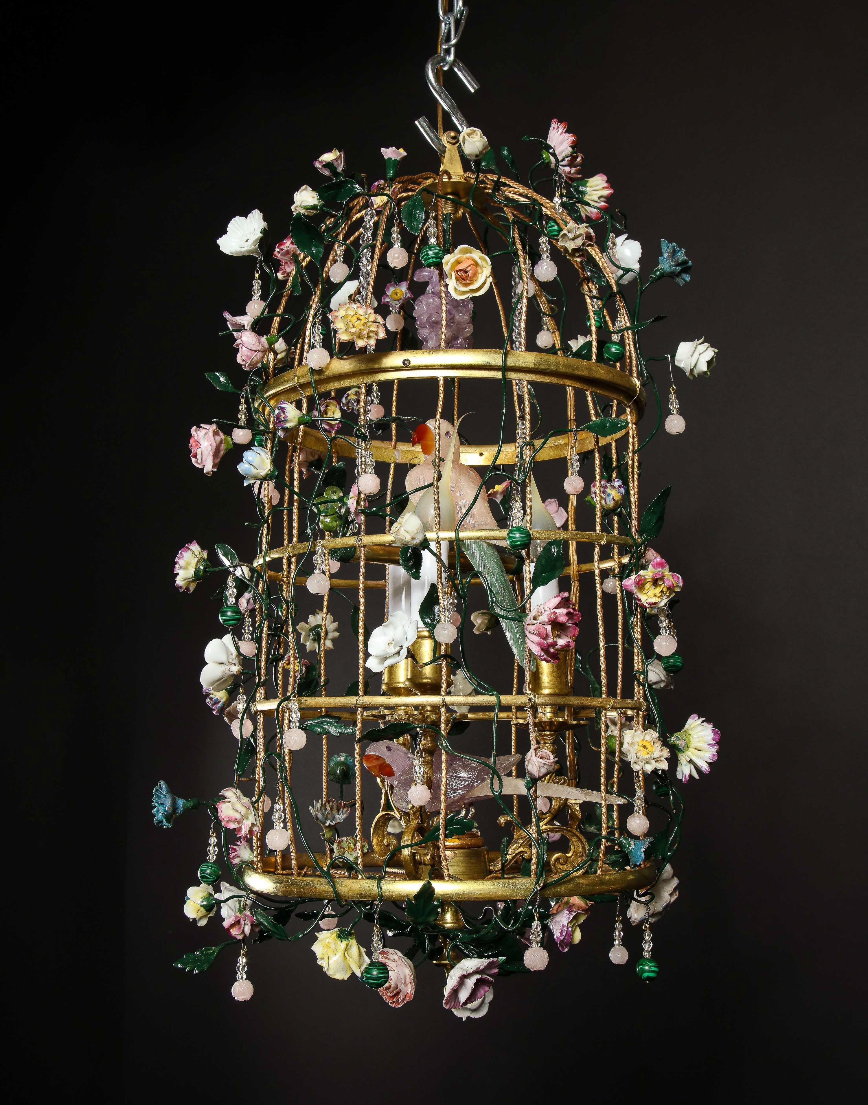 A Magnificent French Louis XVI style Gilt Bronze Birdcage Form Multi Light Chandelier with Two Hand-Carved PInk and Amethyst Rock Crystal Birds Perched on the Inside.  The exterior is highly embellished with multi-colored porcelain enameled flowers