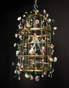 Araña jaula con 2 pájaros de cristal de roca posados en su interior con flores de porcelana