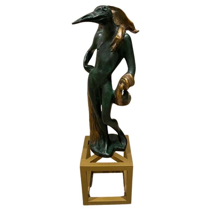 Une intrigante étude en bronze de la fin du 20e siècle, en édition limitée, représentant un personnage mi-homme, mi-oiseau, debout sur un tabouret à quatre pieds. La surface du bronze est patinée d'un vert profond rehaussé d'une dorure brillante.