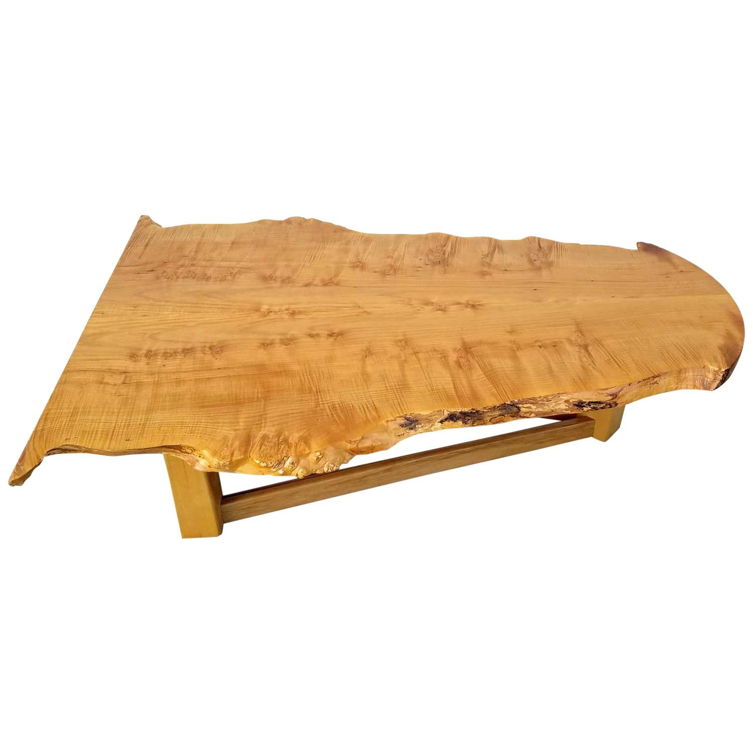 Exceptional bird's-eye maple slab coffee table with natural live edge. This table caught our eye for it's distinctly modern spin on they typical rustic slab. Notice how the top surface has been expertly milled to have a perfect plane. The millwork