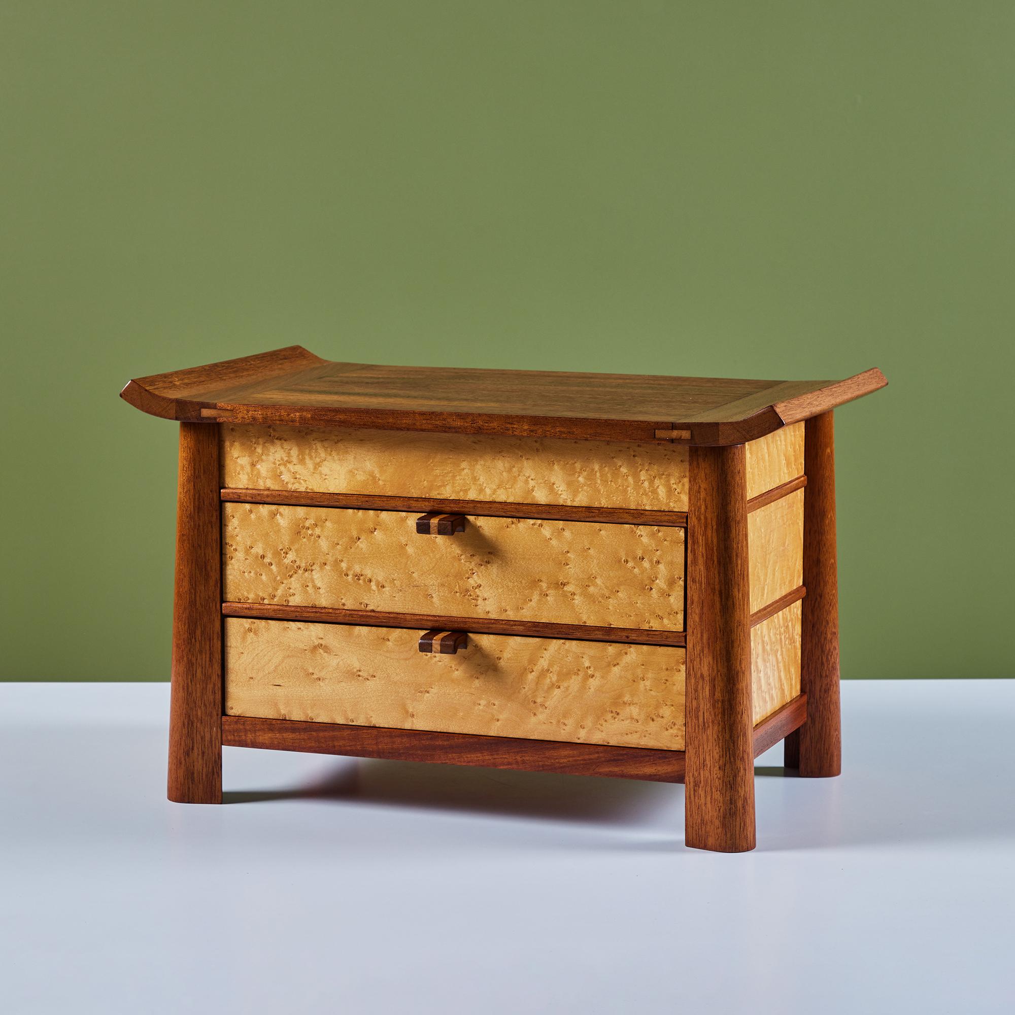 Jewelry chest beautifully crafted with birdseye maple drawers and a mahogany frame. The box features two drawers and a third top compartment when the sculpted wood lid is removed. The box sits slightly elevated on four mahogany legs.

Dimensions
20