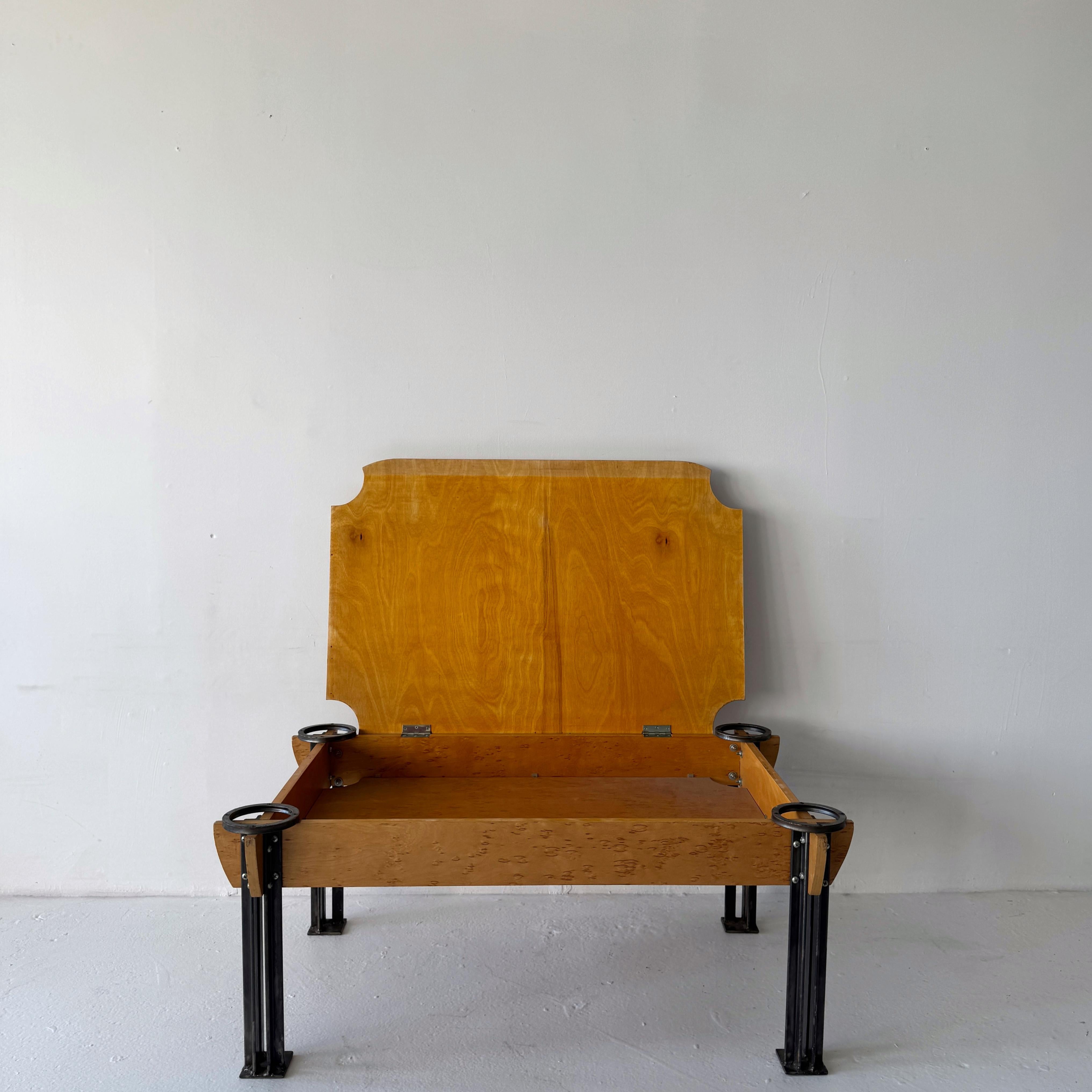 Mesa baja de arce ojo de pájaro con almacenaje oculto y detalles industriales

Una llamativa mesa de centro posmoderna fabricada en arce ojo de pájaro, con un compartimento de almacenaje oculto y elevable. La mesa se asienta sobre esculturales patas