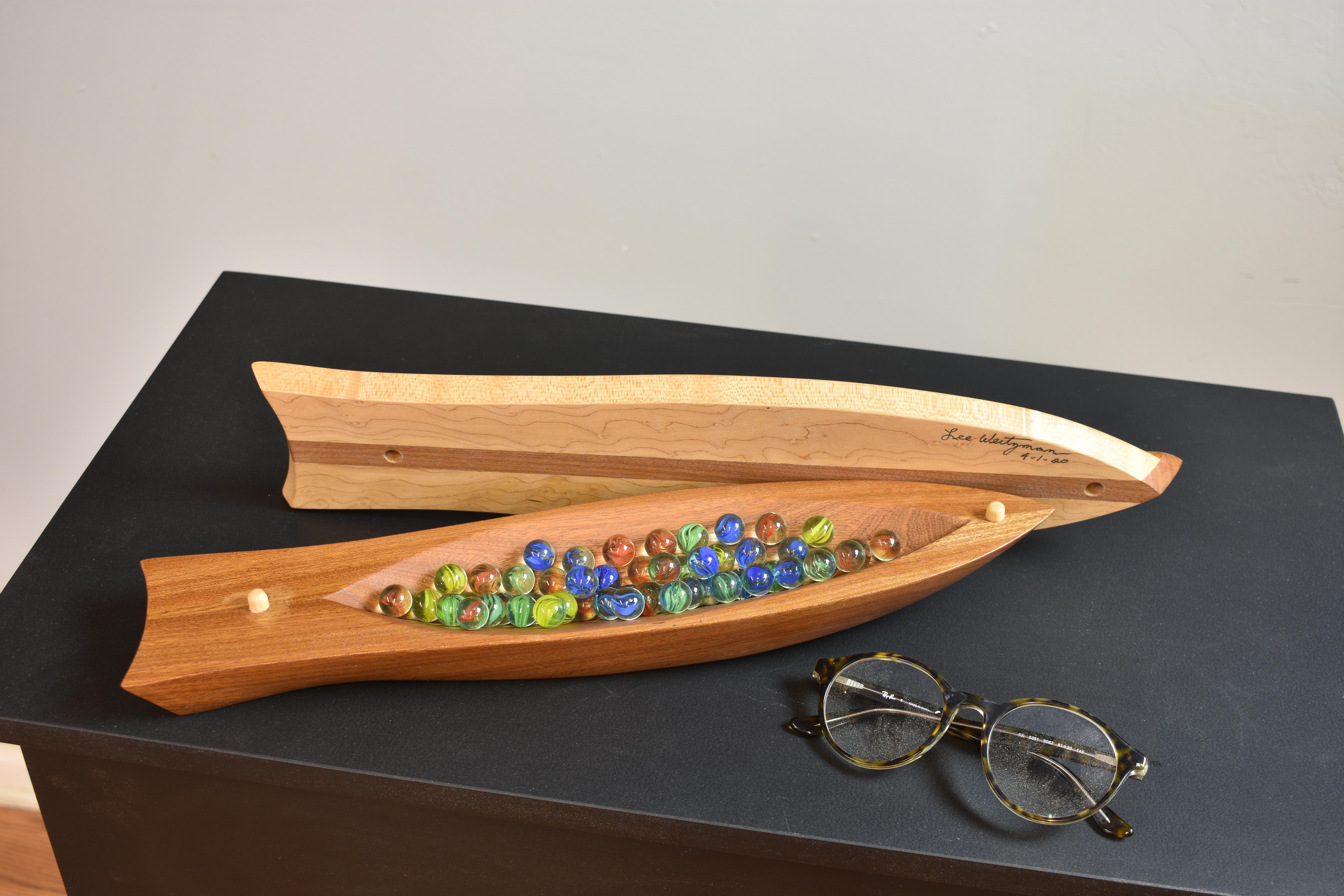 This one-of-a kind sculptural vessel is hand made by Lee Weitzman. It features a birds eye maple top with a central spine of Mahogany with glass fish eyes. When the lid is removed it exposes a small storage space. The bottom 