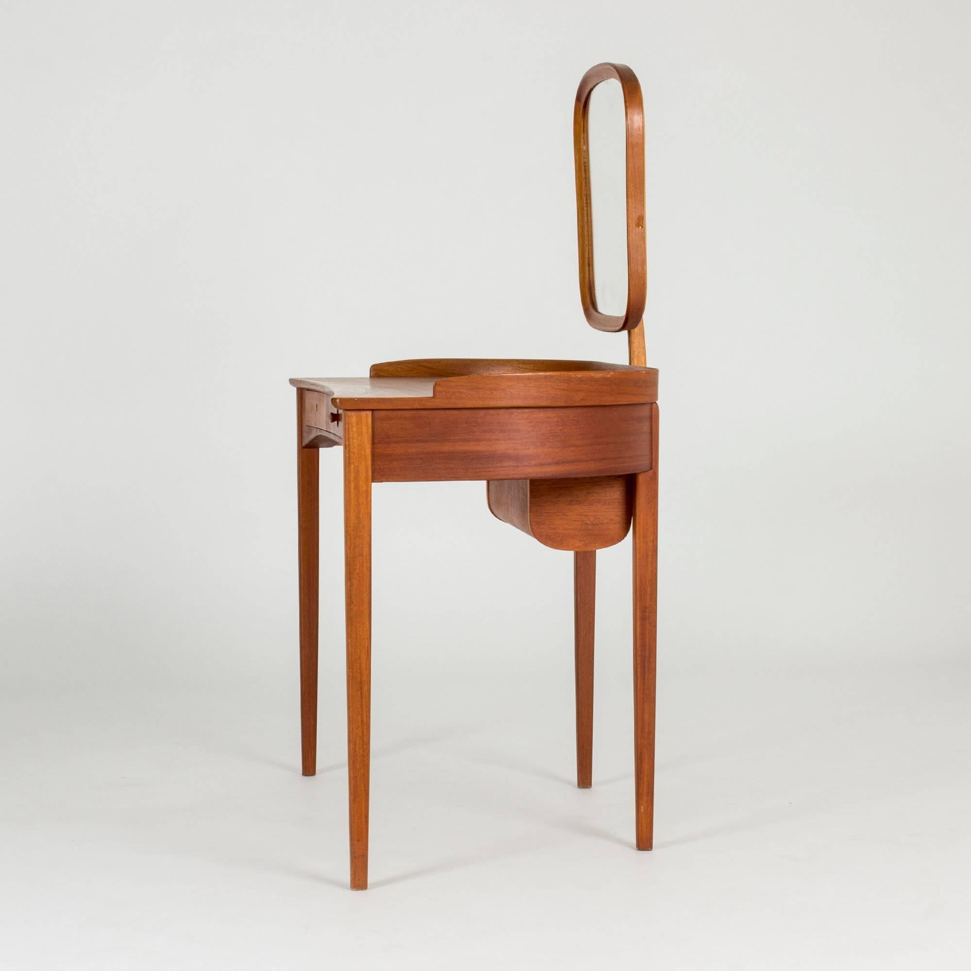 Beautiful “Birgitta” dressing table by Carl Malmsten, made from teak. Neat, curved design. Submerged drawer in the table top, covered by a jalousie door.