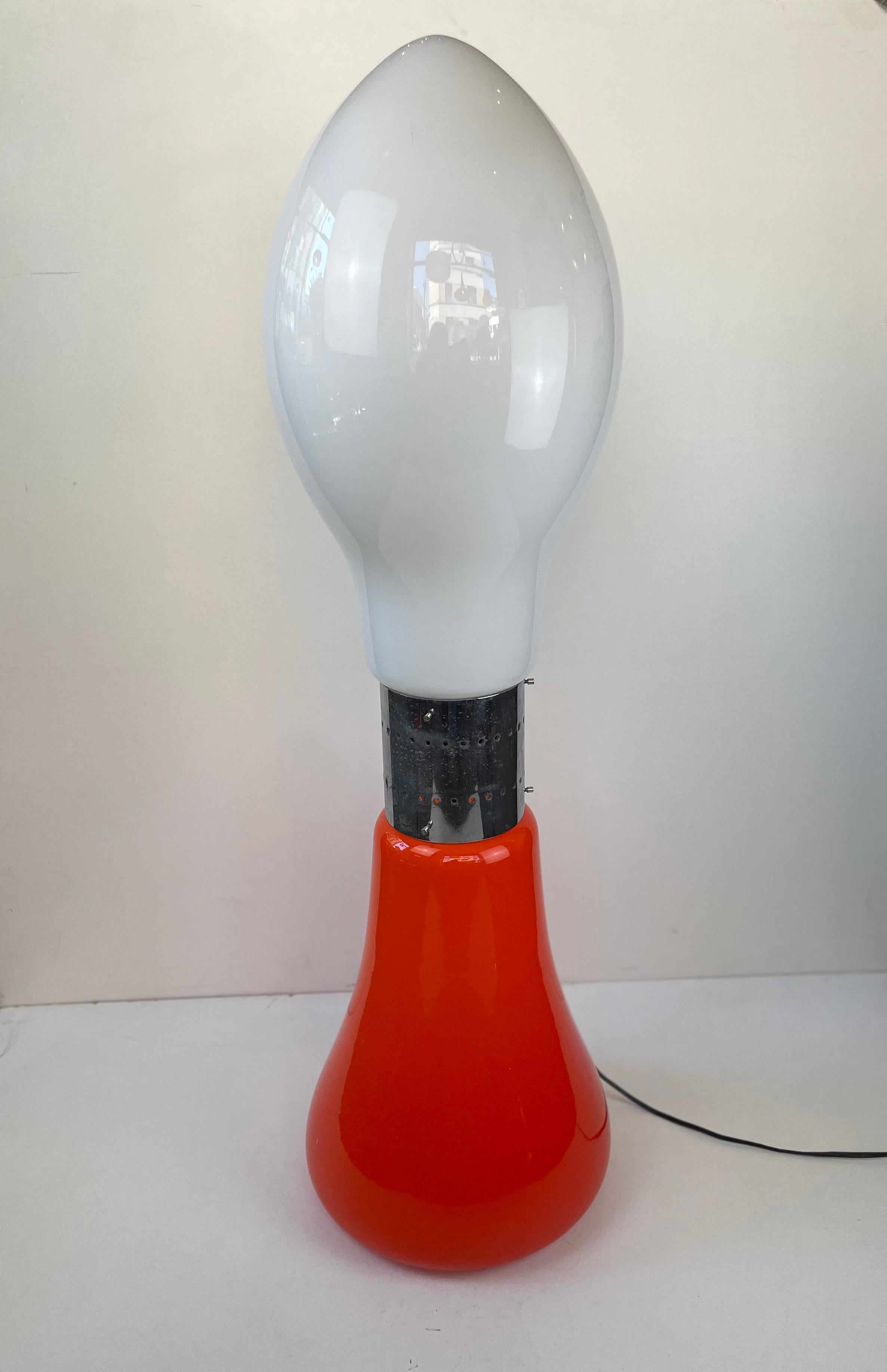Lámpara de pie alta italiana compuesta por dos bombillas de cristal de Murano, una naranja y otra blanca opalina, fijadas por un fleje cromado en el centro. Puede estar todo iluminado o por partes. Diseño icónico llamado Birillo, diseñado por Carlo