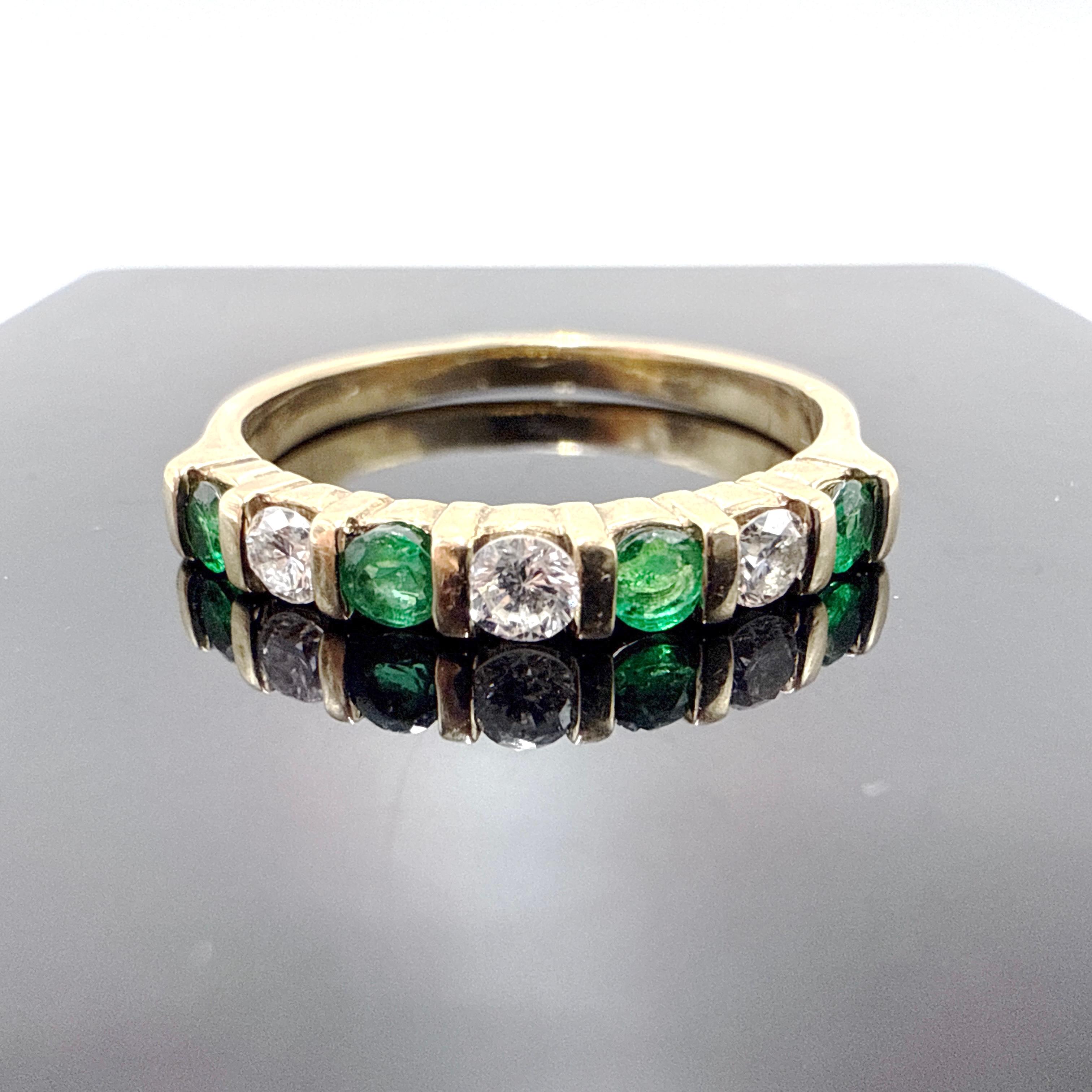 This 14K yellow gold 7-stone band by Birks features a refined and symmetrical design with alternating emeralds and diamonds in horizontal channel settings. The ring is wax cast and hand finished, tapering from 2.90 mm at the top to 2.30 mm at the