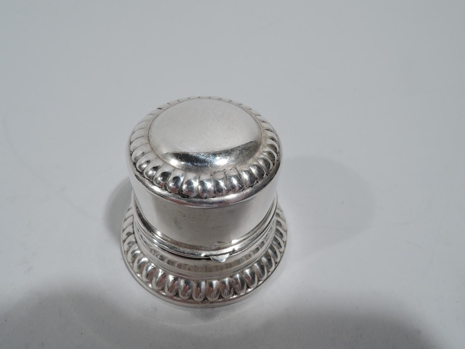 Classical sterling silver ring box. Made by Birks in Canada. Round with straight sides and hinged cover. Cover top has vacant center and gadrooned rim. Spread foot also gadrooned. Box interior has fitted velvet for a single ring. Cover interior gilt