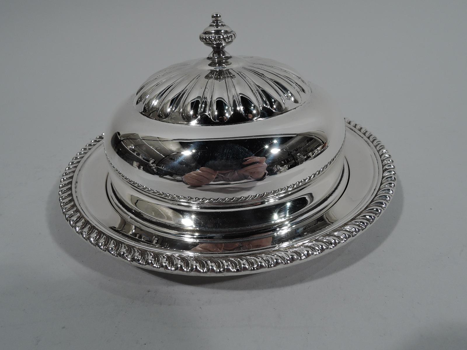 Georgian-style sterling silver butter dish. Made by Birks in Canada in 1950. Round and deep well, and gadrooned rim. Cover domed; beaded finial surrounded by alternating flutes and gadroons. Cut-glass liner. Fully marked including London date letter