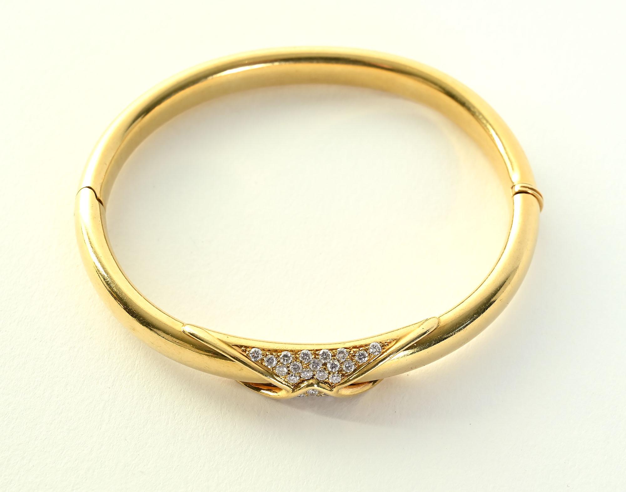 Hinged bangle bracelet of 18 karat gold and diamonds by Birks, the Tiffany of Canada. The bracelet has 32 diamonds weighing approximately .65 carats. They gracefully fold over the center of the oval bracelet. The inner diameter is 2 5/16