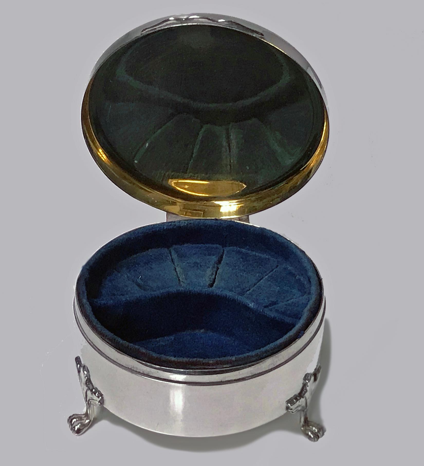 Vintage Birks Sterling Silver Jewellery Box, 1949. The box of circular form on three acanthus supports, plain body, the hinged cover with foliate scroll engraving centering a monogrammed panel, interior cover original gilding. The box interior with