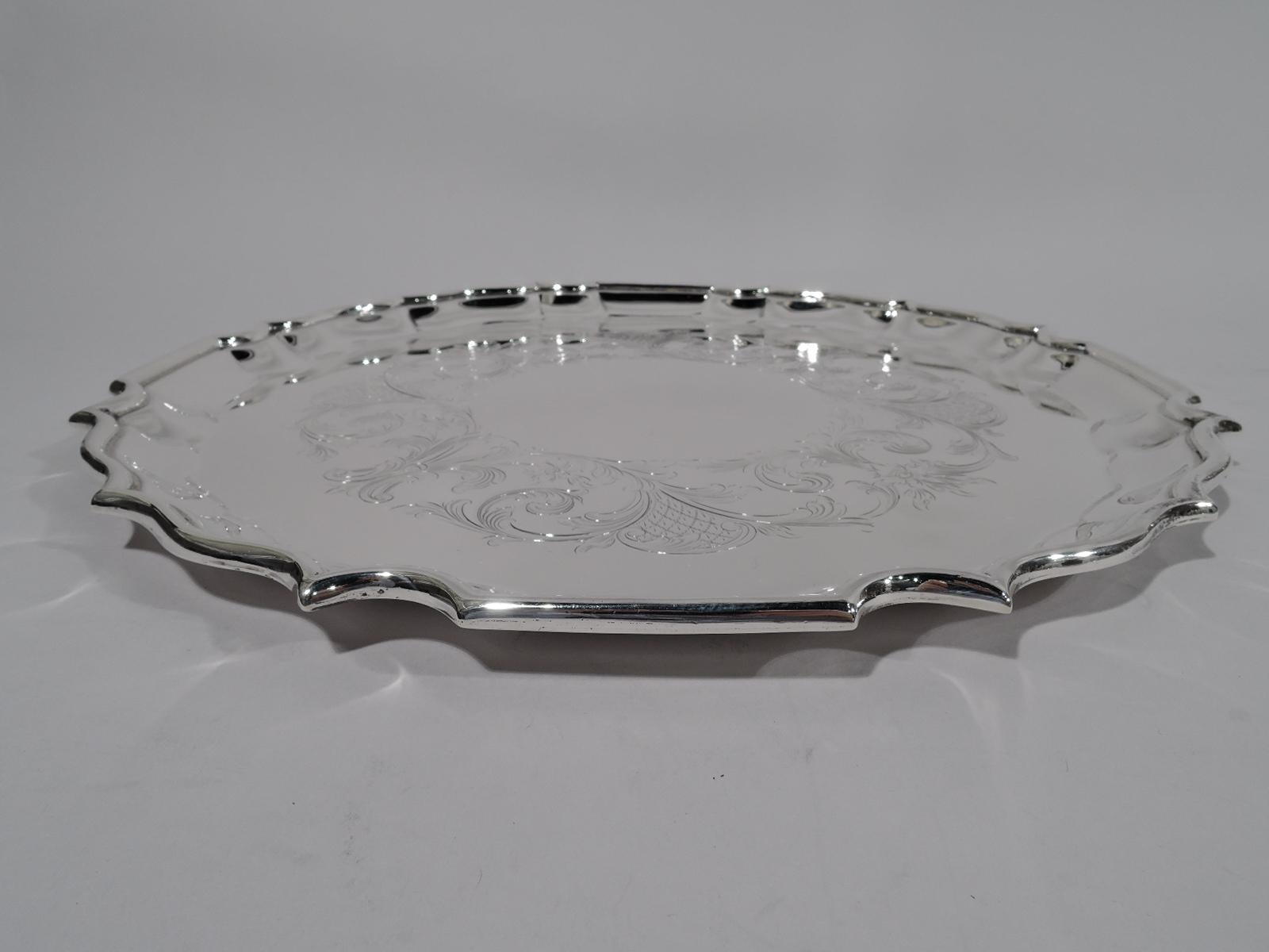 Georgian sterling silver serving tray. Made by Birks in Canada in 1931. Round with curvilinear piecrust rim. Well has engraved leafy wreath (vacant). Traditional with nice heft. Fully marked including maker’s stamp, no. 63/9, and date letter. Heavy
