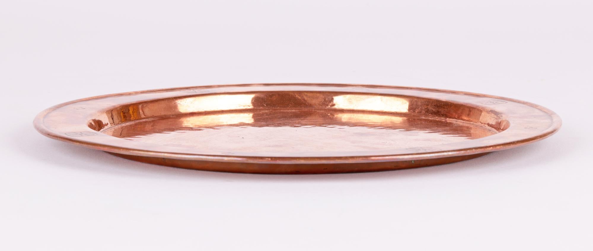 A stylish and heavily hand-crafted Birmingham Guild Arts & Crafts copper paten or tray dating from around 1915. The tray of flat circular shape has a raised flat rim decorated with incised cross designs in a pagan or Pugin style with smaller designs