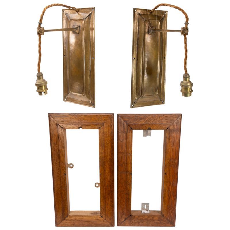 Birmingham Guild of Handicraft.
A rare pair of Arts and Crafts patinated bronze wall lights, each with raised fielded panels to the backplates and forged bracket arms. Housed in quarter-sawn oak surrounds with chamfered edges and original mountings.