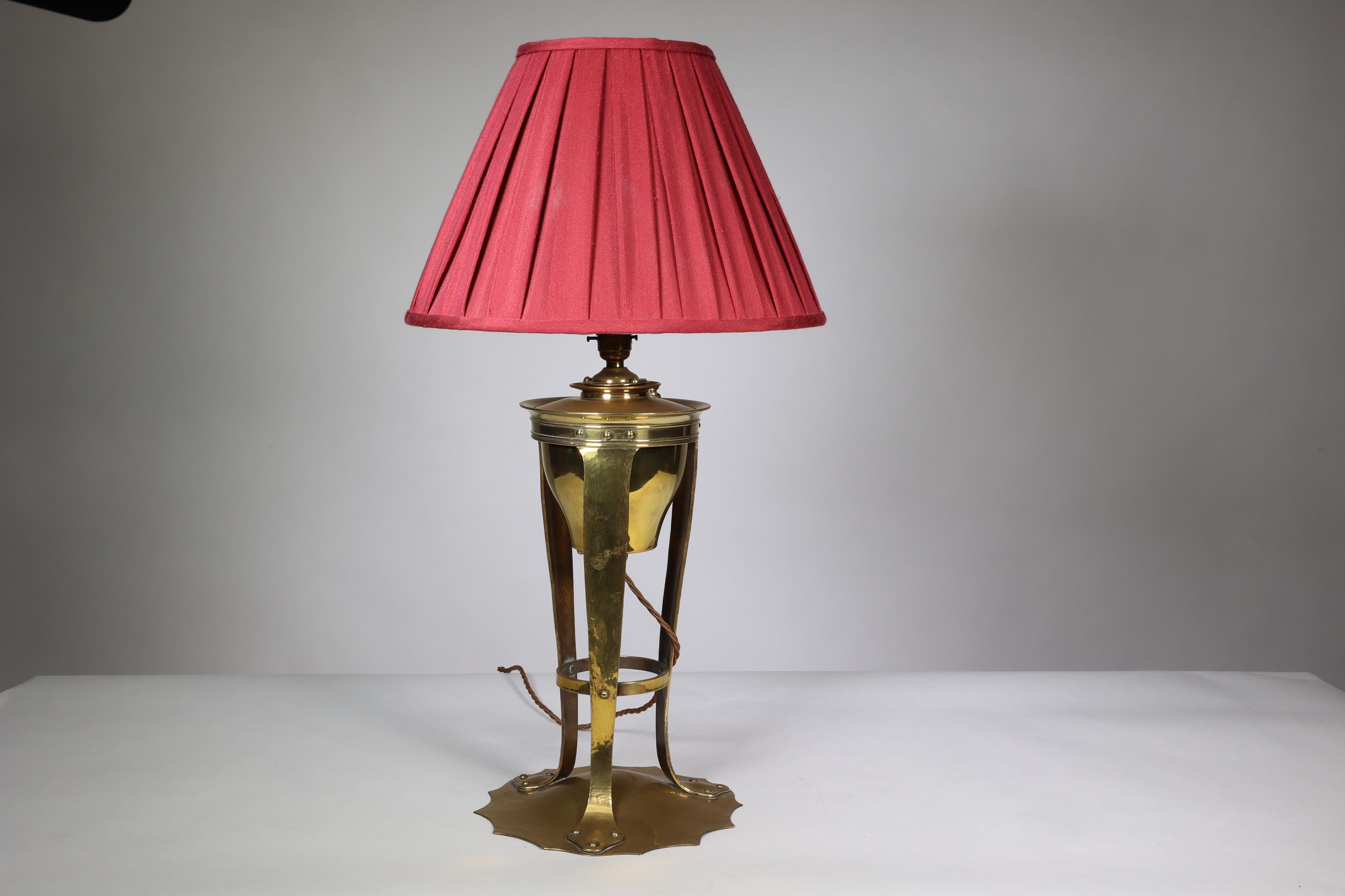 Arthur Dixon for the Birmingham Guild of Handicraft. A rare Arts and Crafts brass table lamp with removable font raised on three supports cold riveted to a lily pad base. Converted to electricity.