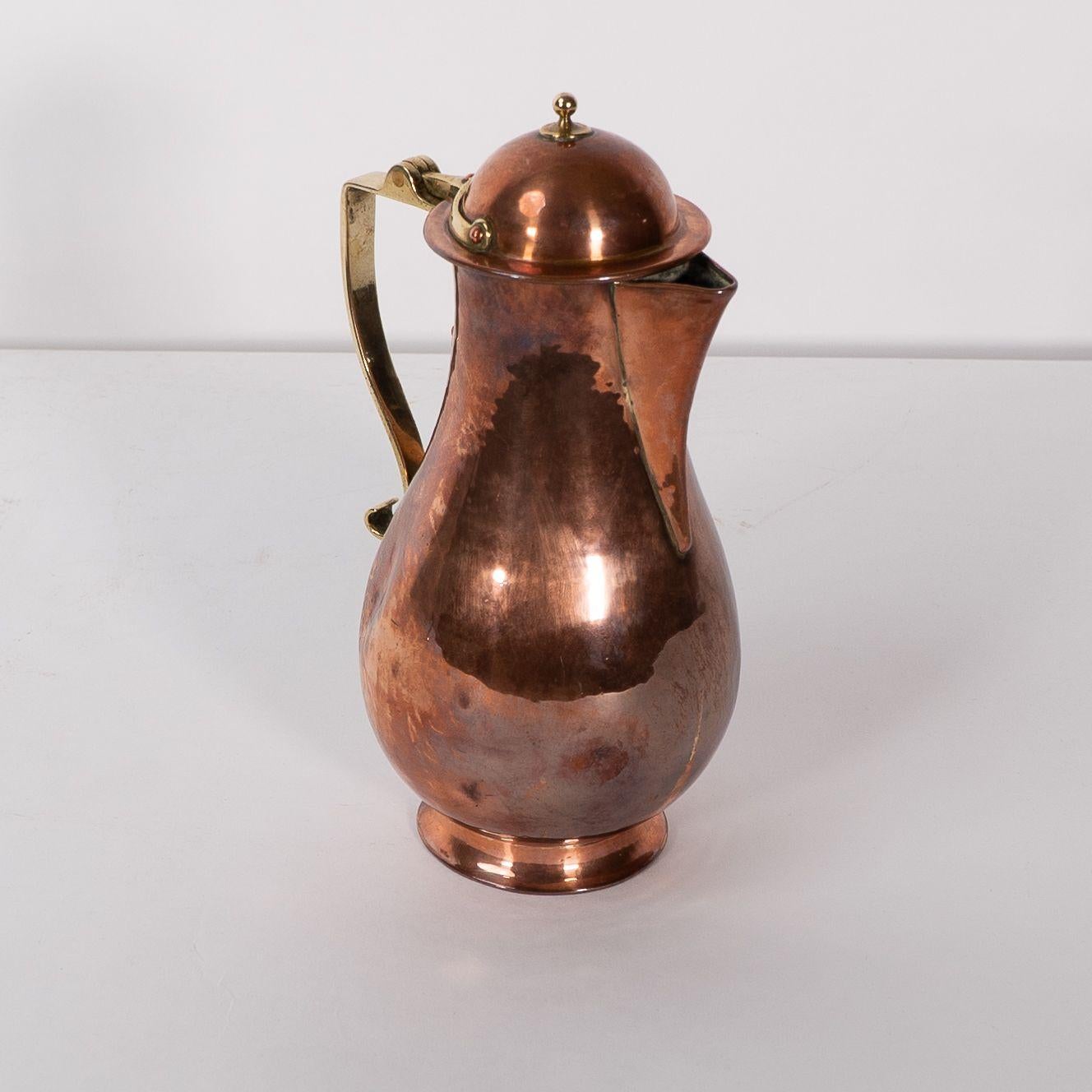 The Birmingham Guild of Handicraft. An Arts and Crafts heavy gage copper and brass chocolate jug with an intricate handle, lid and support mechanism incorporated into the design. Stamped to the base ''The Birmingham Guild Ltd. England. Their motto