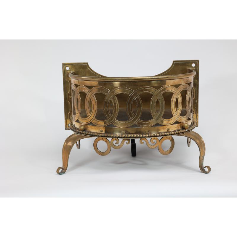 Birmingham Guild of Handicraft attributed. A gilded semi-circular brass planter with a shaped back plate, incised interlocking circles, and a row of beaded decorations with circles, standing on shaped and curved feet.
