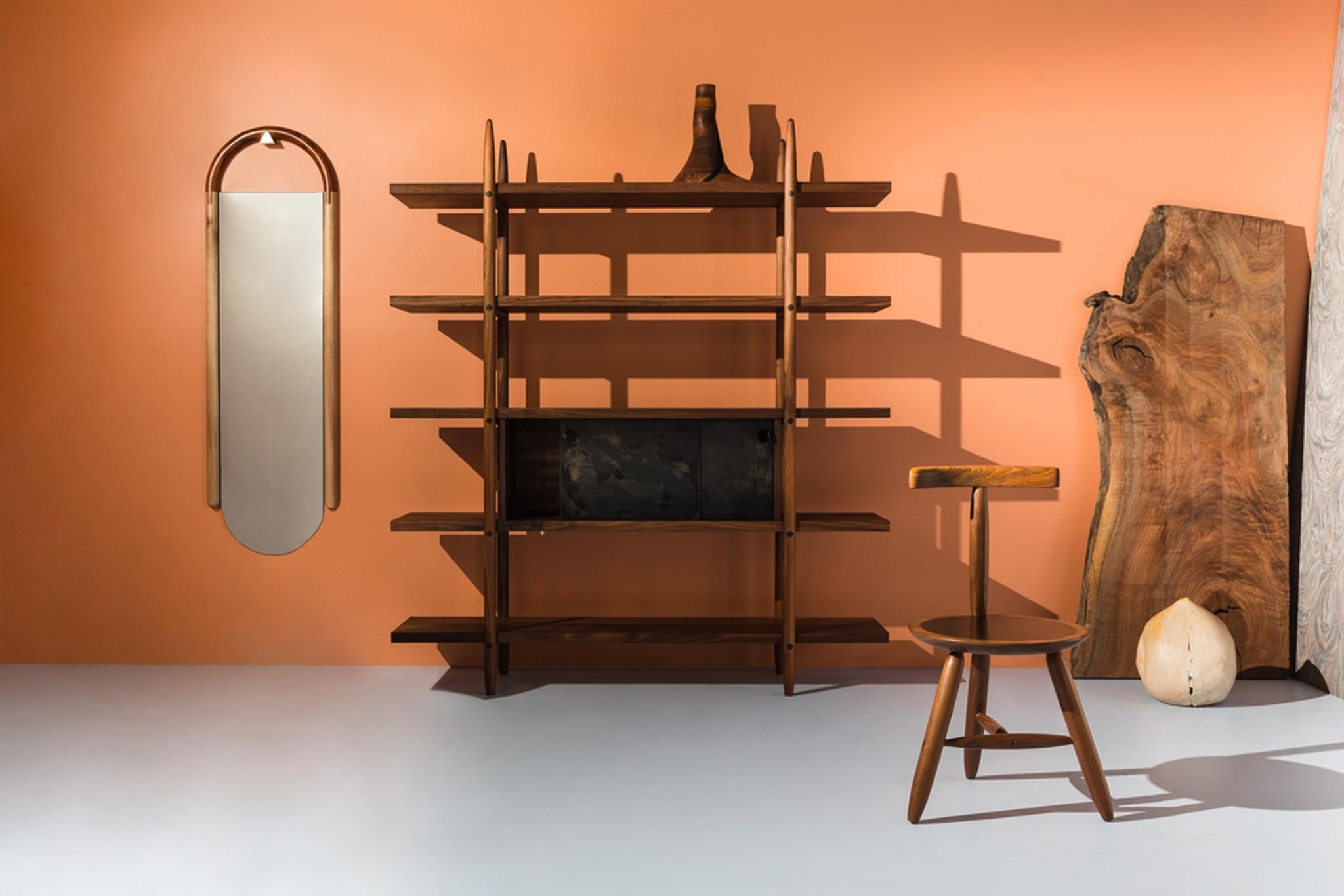 This handmade bookshelf is made of wood by Birnam Wood Studio in New York. This contemporary shelving design is heavily influence by traditional mid-century modern silhouettes. The box cupboard on the second shelf has sliding drawers that open and