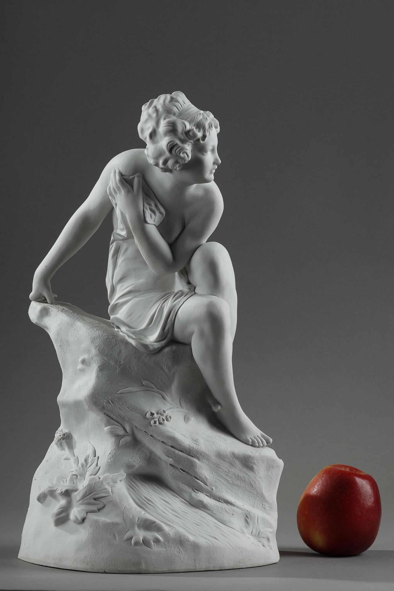 Statuette aus Biskuitporzellan, die eine nackte Frau auf einem Felsen sitzend darstellt, nach dem italienischen Bildhauer Raphaël Nannini. Auf der Rückseite eingraviert: 