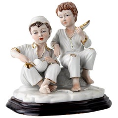 Statuette en porcelaine biscuit représentant deux garçons mangeant un melon avec des détails dorés