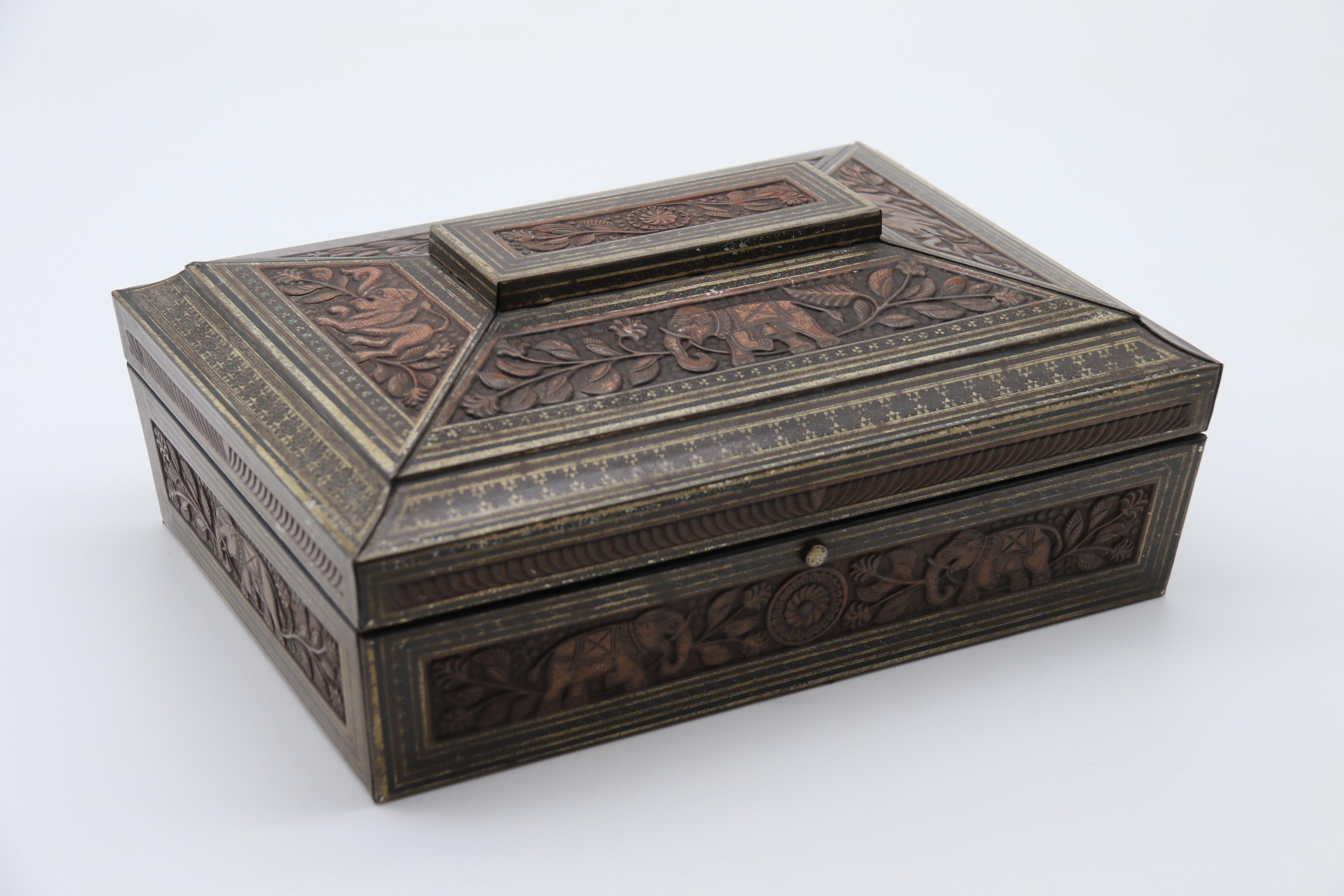 Cette rare survivante, une boîte à biscuits Hunter et Palmer de fantaisie, a été fabriquée à partir de tôle emboutie et imprimée par transfert pour ressembler exactement à une véritable boîte en bois dur indien du 19e siècle. Il est sculpté