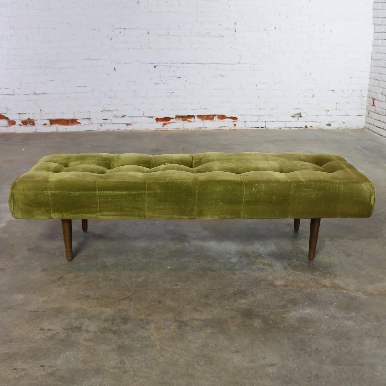 Interesting midcentury and/or Hollywood Regency upholstered and biscuit tufted bench. This piece still retains its original avocado green velvet upholstery and, if you like age patina, it could be used; however, there are a couple buttons missing