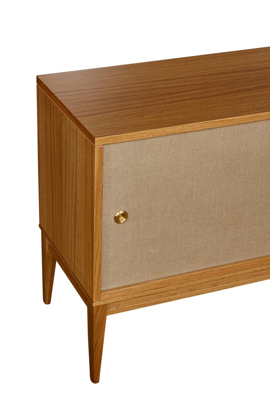 Cerused oak console on solid tapered leg base with Belgium linen sliding doors detailed with solid brass finger pull hardware. Interior has adjustable shelving and cerused finish to match exterior. 

 Custom orders have a lead time of 10-12 weeks