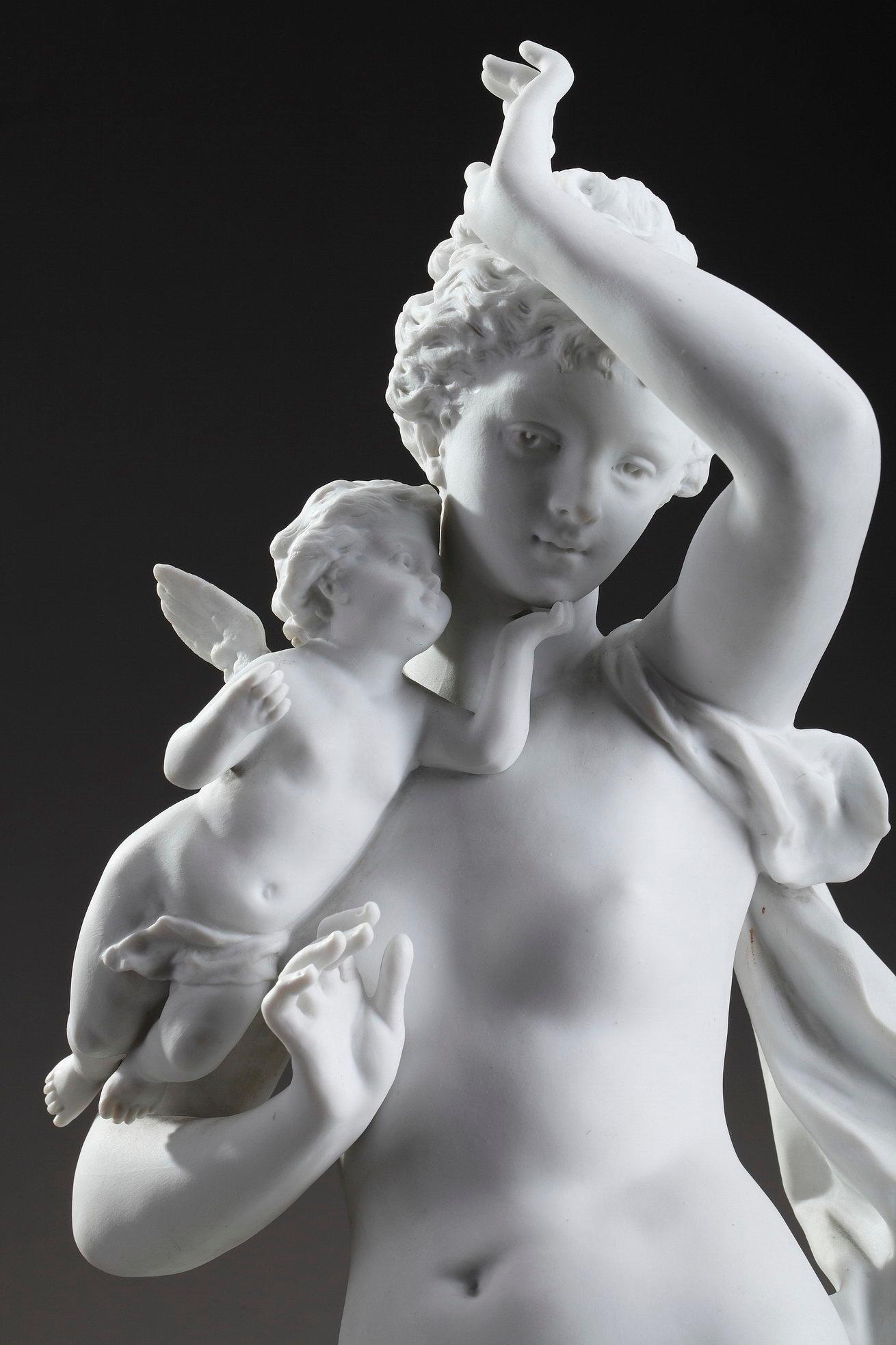 Art Nouveau bisque, porcelain, figurine featuring Venus in the company of two Cupids by Ernest Rancoulet (French, 1870-1915). One of them holds a cornucopia, and the other one touches her face tenderly. Venus leans against a column adorned with