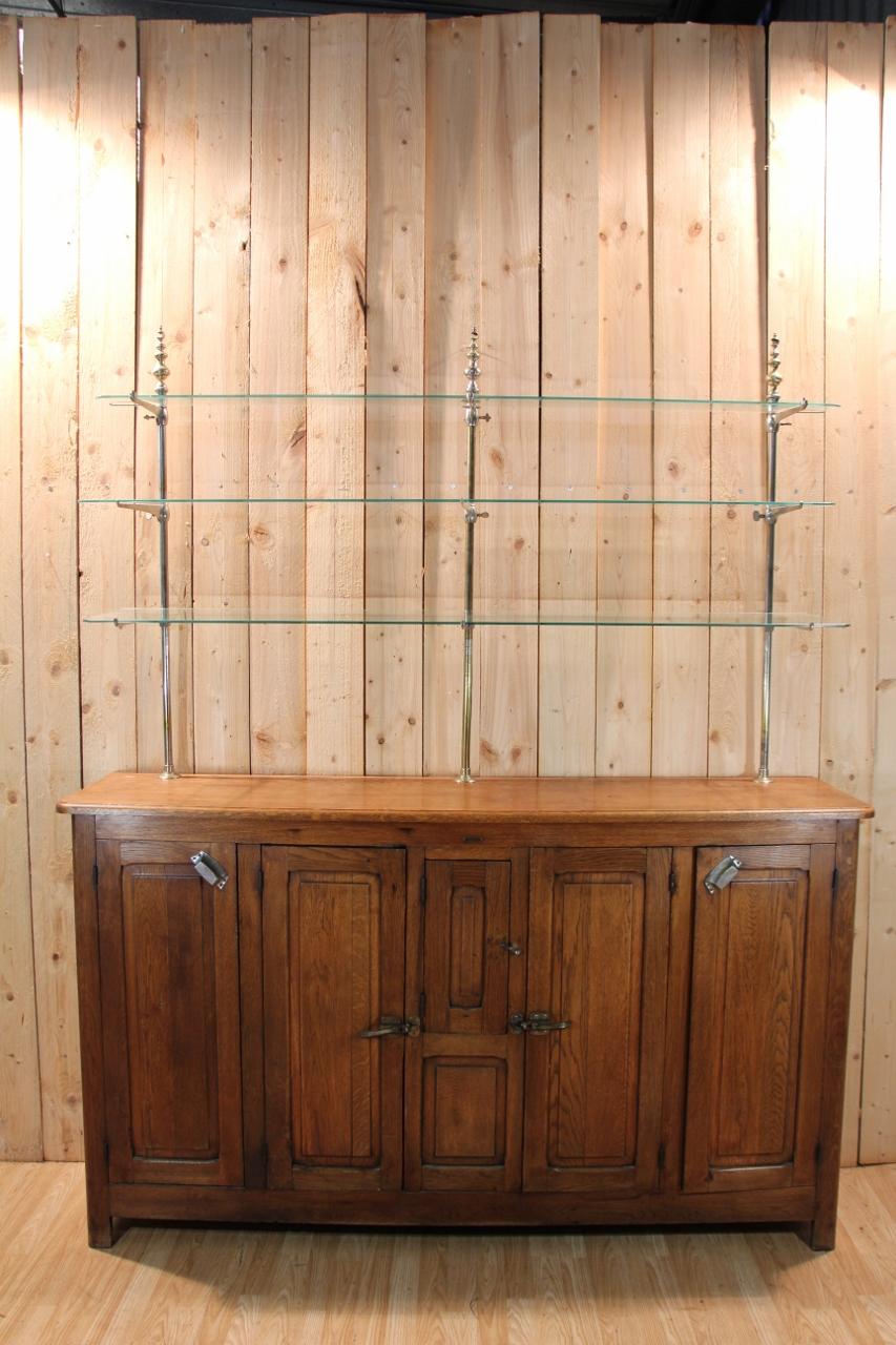 Barra de principios del siglo XX con su barra trasera en muy buen estado, naturalmente con signos de desgaste y uso. El bar conserva su encimera original de zinc y dos fregaderos de cobre; la nevera interior está presente. La barra trasera consta de