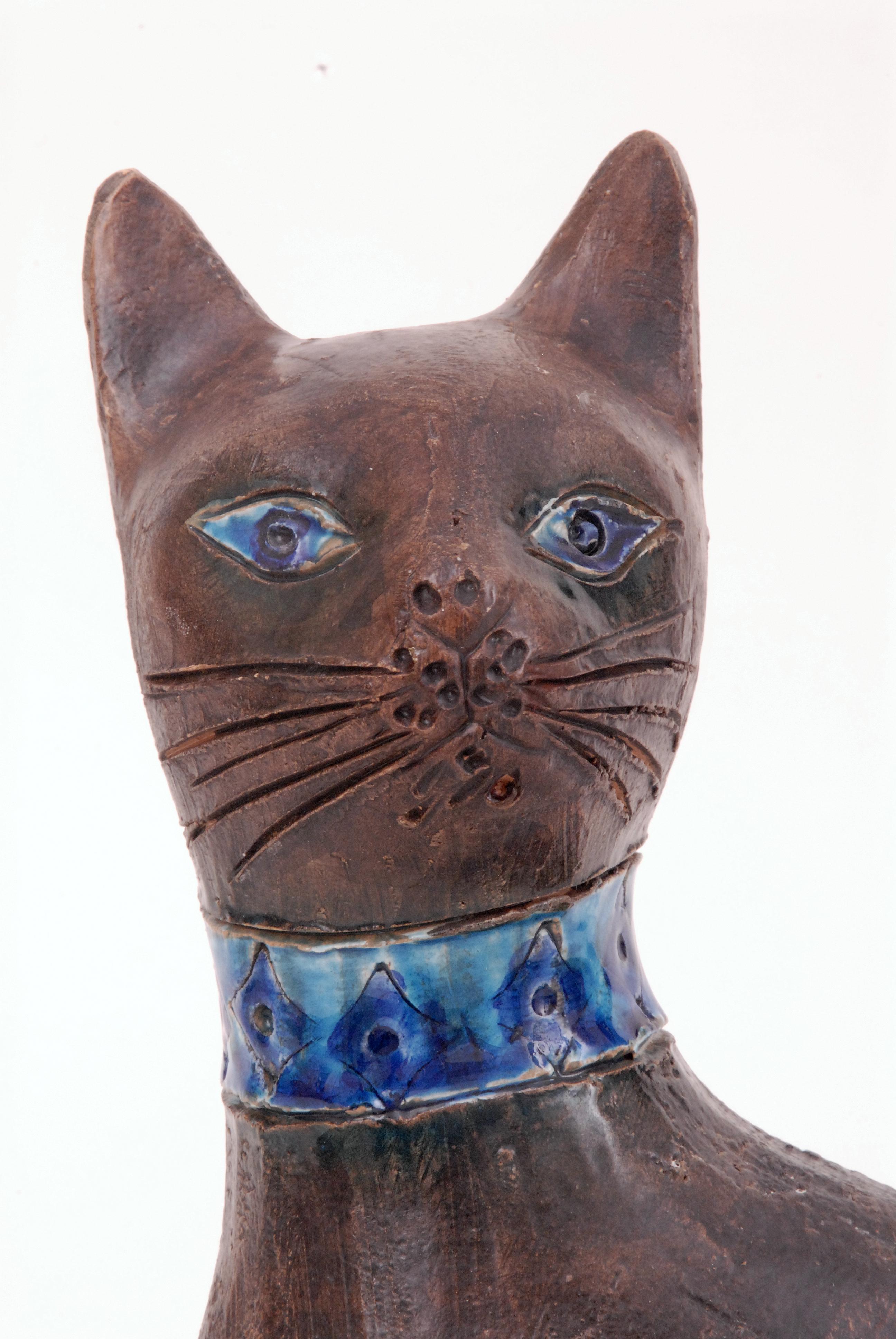 A sitting cat with the Moorish 'Moresco' pattern designed by Aldo Londi in 1963 and produced until circa 1970. Impressed with stylized foliate and diamond motifs and glazed panel and neck collar in blues on a manganese-brown glazed body and head. A