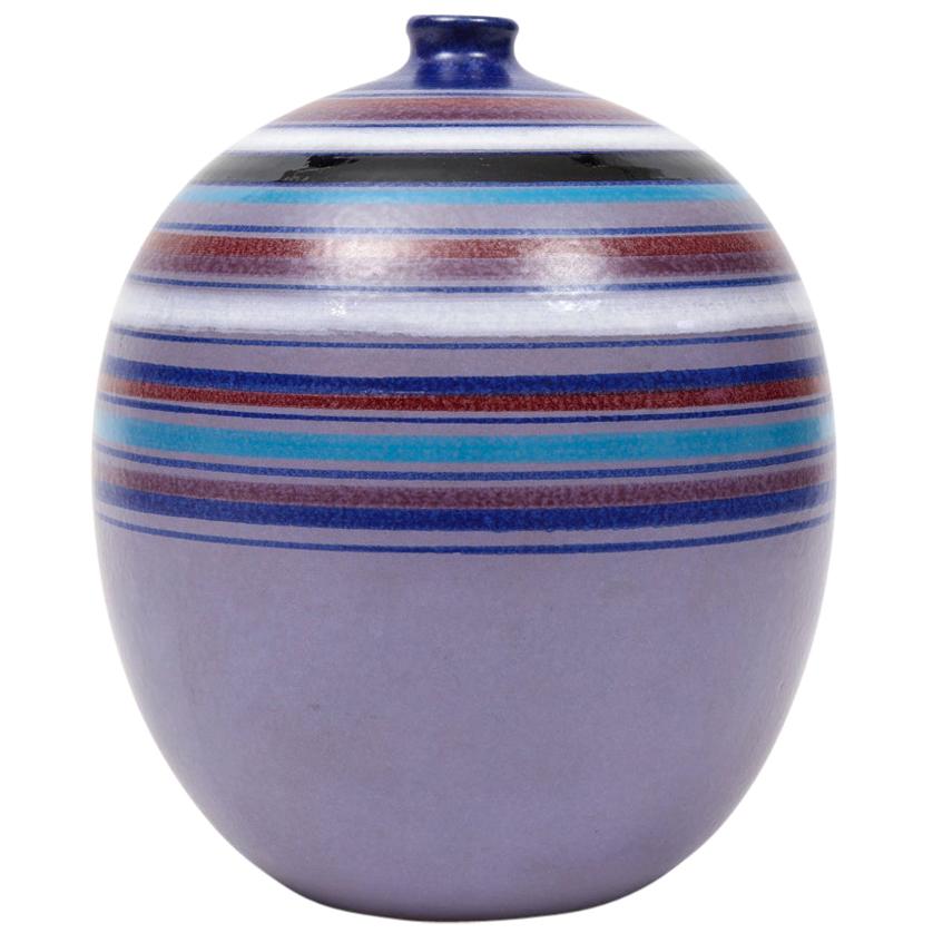 Bitossi ball vase, stripes, purple blue, white, red, signed. Chunky medium scale lavender glazed spherical vase with tight hard edge stripes in blue, white, black, and various shades of reds and purples. Signed on the underside: 