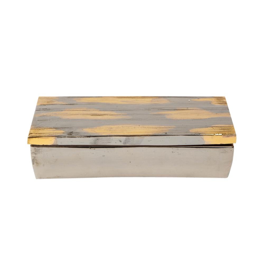 Bitossi box, ceramic, brushed metallic gold, chrome silver. Small scaled lidded box with a finely textured ribbed abstract top, glazed in gold and chrome, and a metallic platinum bottom. Faded paper import label on the underside of the box.

  